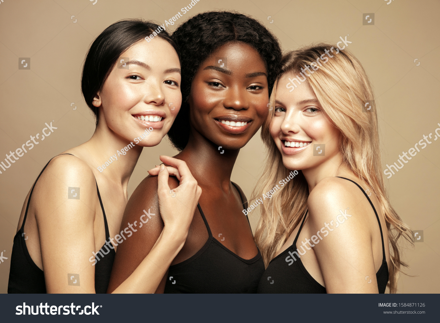 Beauty. Multi Ethnic Group of Womans with diffrent types of skin together and looking on camera. Diverse ethnicity women - Caucasian, African and Asian posing and smiling against beige background. #1584871126