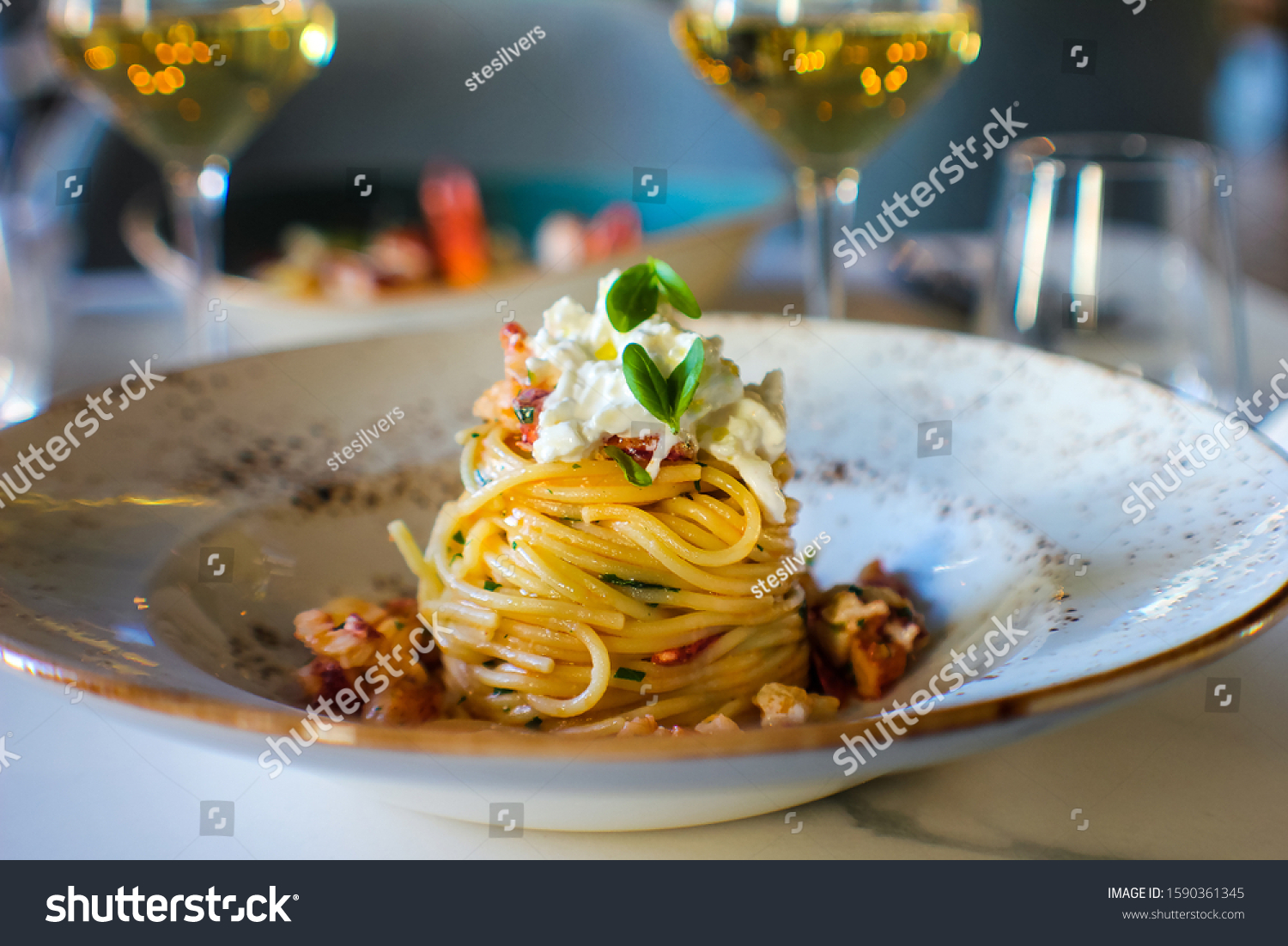 haute cuisine dish with spaghetti with lobster, buffalo stracciatella and a fine white wine. In a luxurious Italian restaurant #1590361345