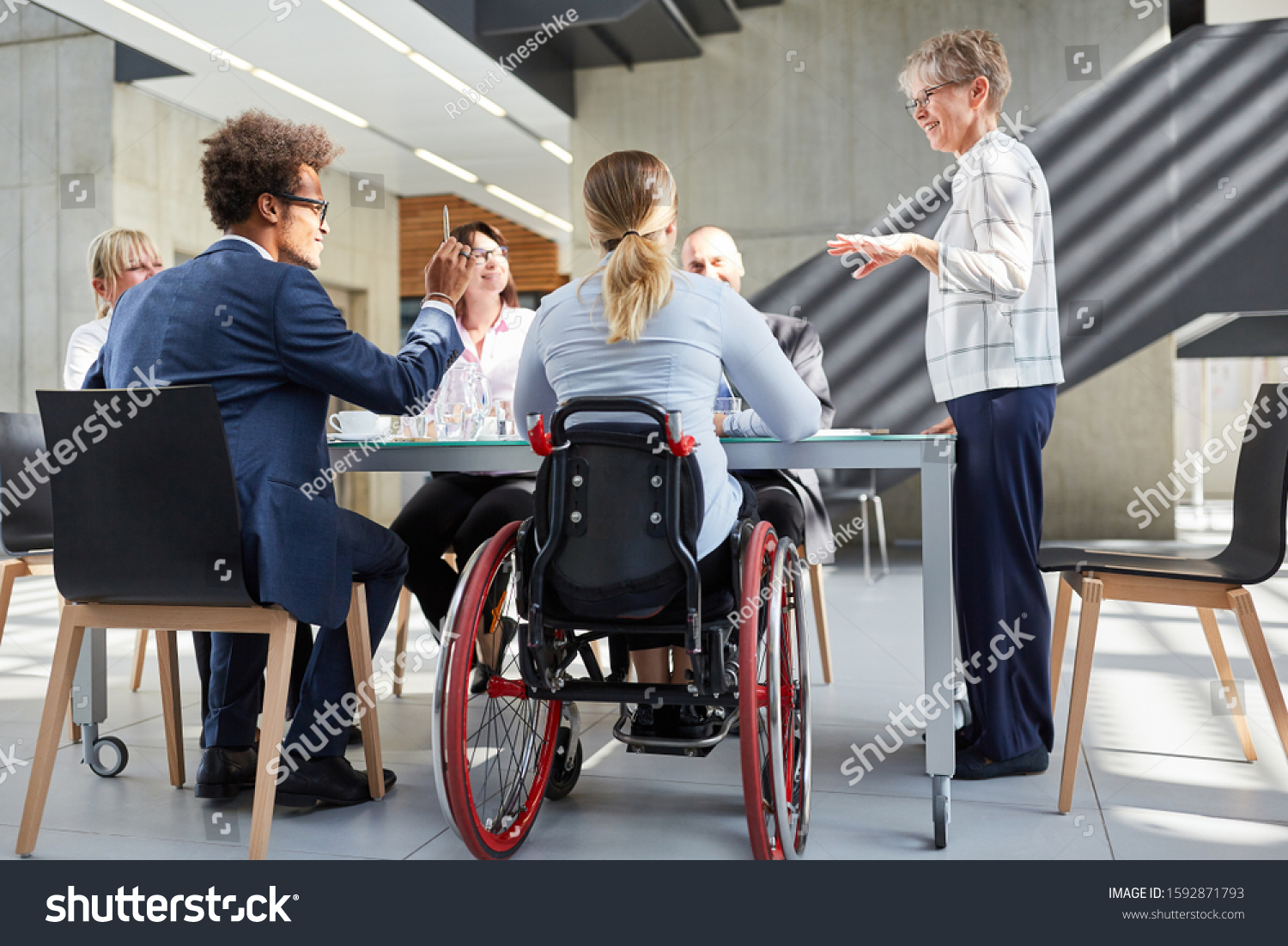 Group of business people in a meeting with colleague in a wheelchair for inclusion #1592871793