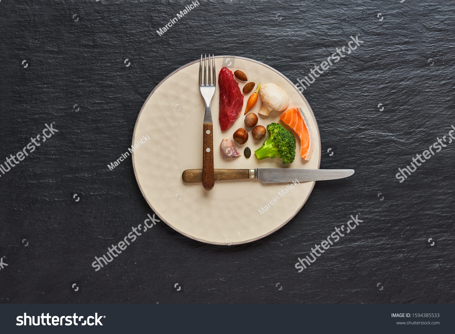  20:4 fasting diet concept. One third plate with healthy food and two third plate is empty. Beef, salmon, egg, broccoli, tomato, nuts, carrots, mushrooms. Dark background. Top view. #1594385533