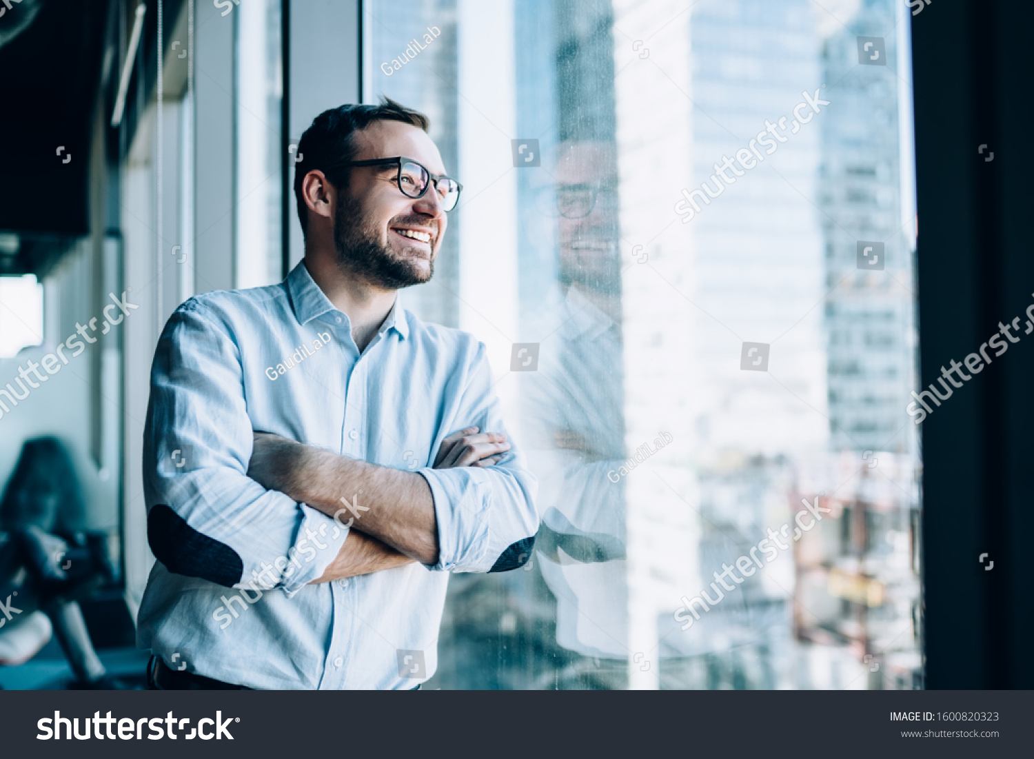 Cheerful male entrepreneur with crossed hands standing near office window view and smiling during work day in company, Caucasian successful corporate boss feeling good from wealthy lifestyle #1600820323