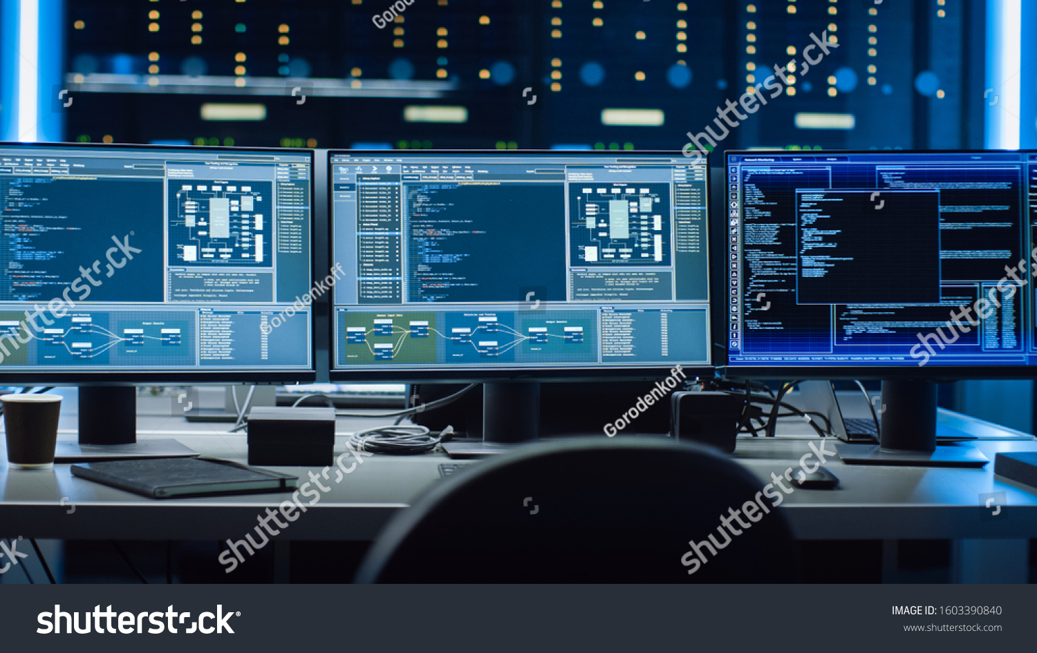 Shot of Multiple Personal Computer Monitors Showing Coding Language Program with System Monitoring Interface. In the Background Data Center with Server Racks. #1603390840