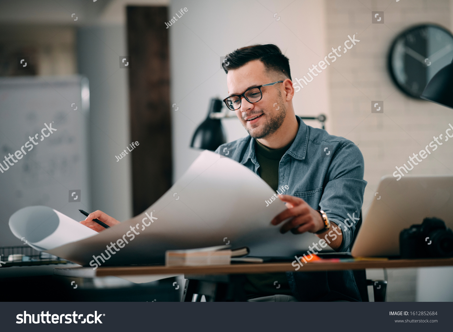 
Architect Engineer Design Working Planning Concept.
Portrait of a smiling young businessman working on blueprints at the office. #1612852684
