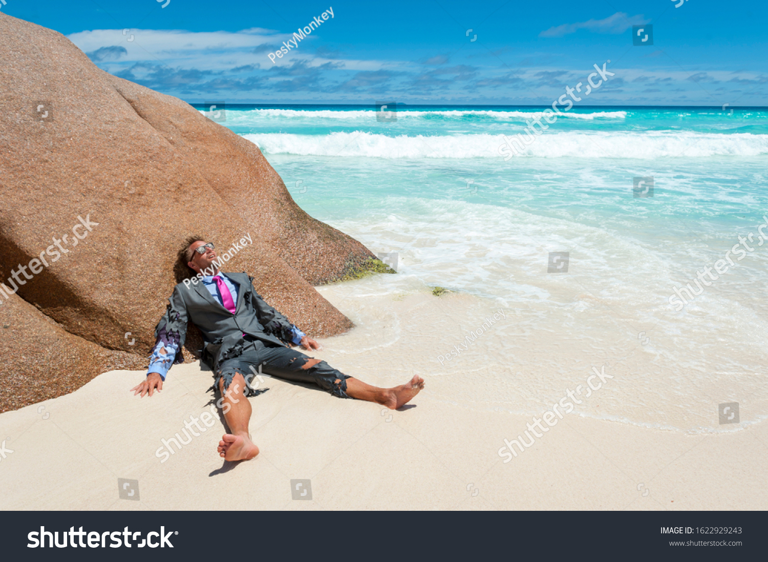 Survivor castaway businessman washed up on a tropical beach in a ragged torn suit #1622929243