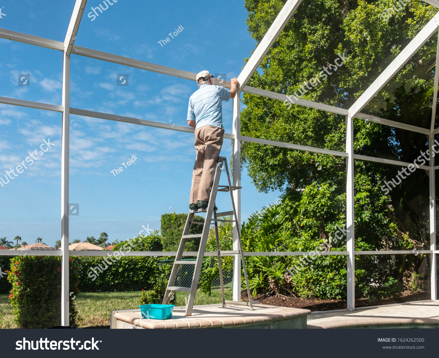 Handyman on ladder cleaning outdoor pool cage enclosure. Screened swimming pool lanai maintenance and screen repair. #1624262500