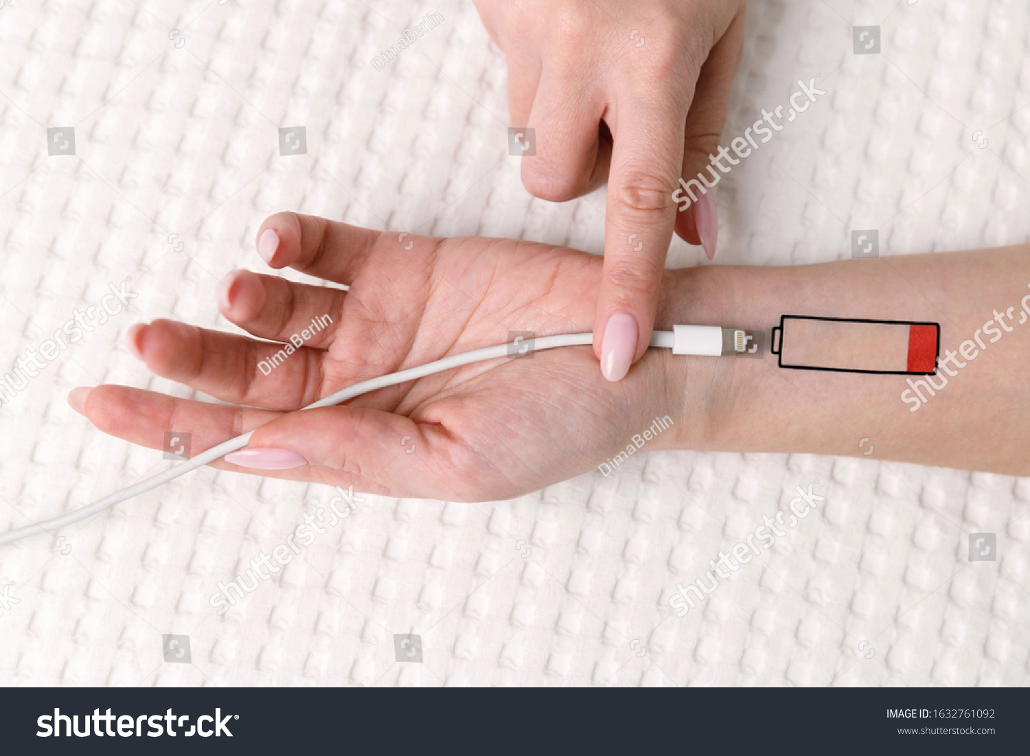 Low battery symbol drawn on human hand. Tired woman lying on the bed, trying to charge from USB, holding cable with your finger. Overwork, exhausted, chronic fatigue, living energy concept.  #1632761092