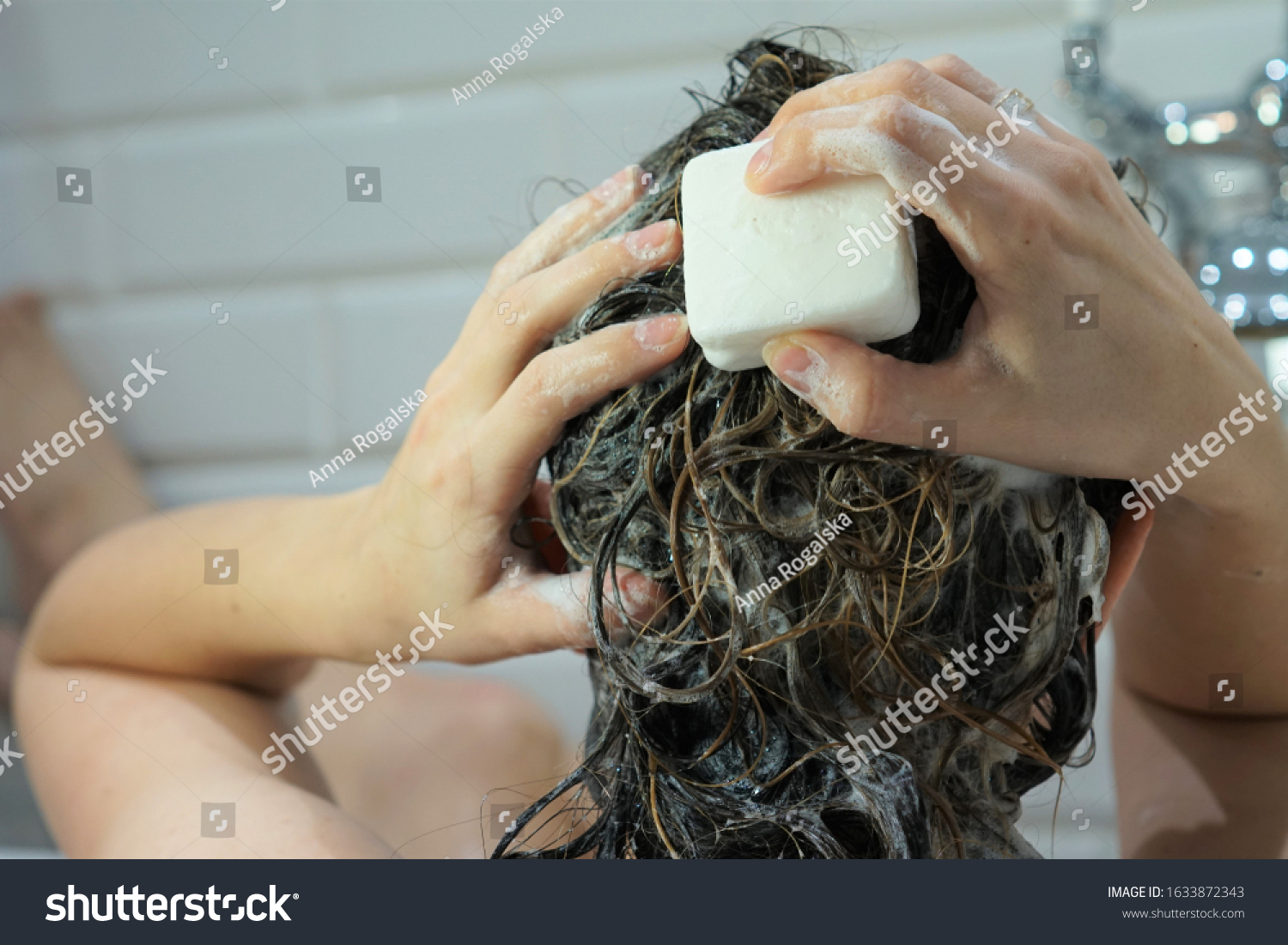 Caucasian woman washes her brown hair with shampoo bar or soap, zero waste concept #1633872343