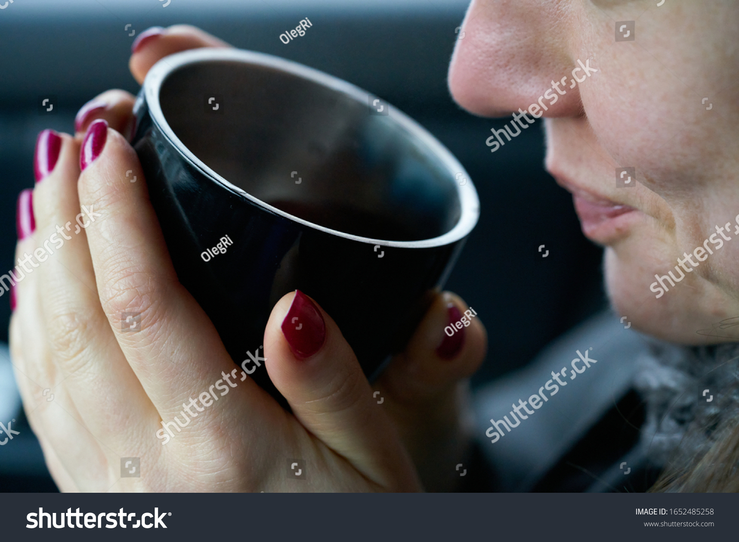 Young woman sits in the trunk of the car and holds a cup of hot drink in her hands #1652485258