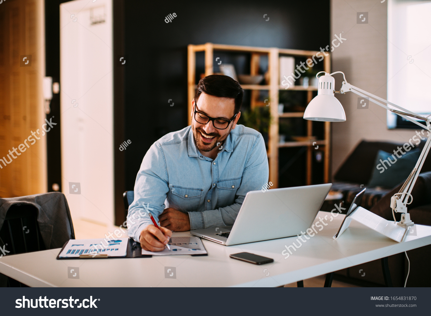 Young business man working at home with laptop and papers on desk #1654831870