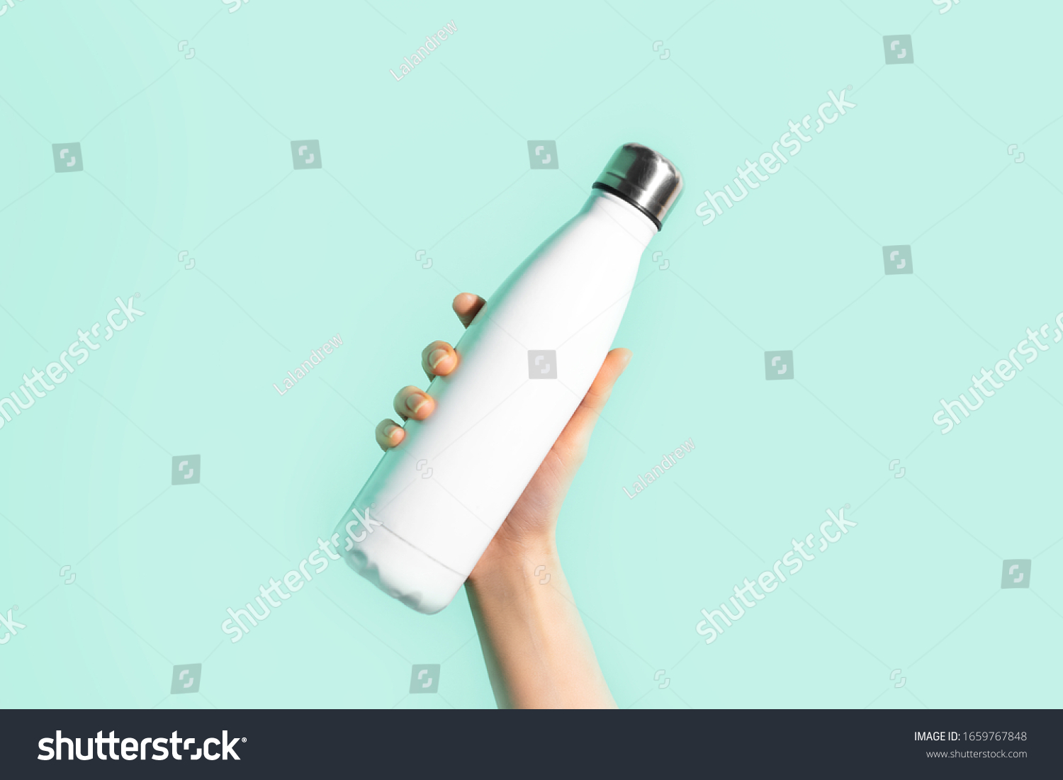 Close-up of female hand, holding white reusable steel stainless eco thermo water bottle with mockup, isolated on background of cyan, aqua menthe color. Be plastic free. Zero waste. #1659767848