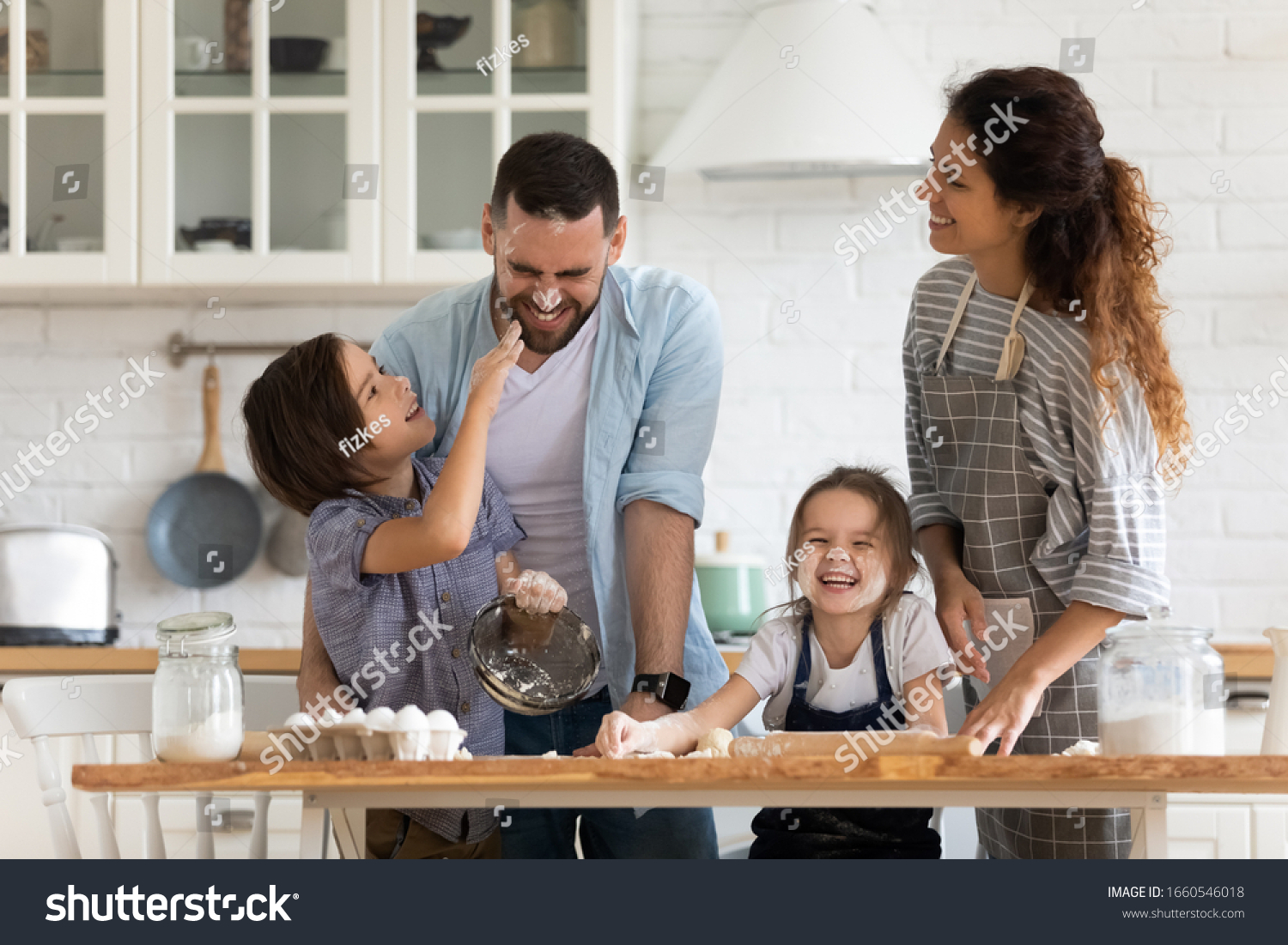 Overjoyed young family with little preschooler kids have fun cooking baking pastry or pie at home together, happy smiling parents enjoy weekend play with small children doing bakery cooking in kitchen #1660546018