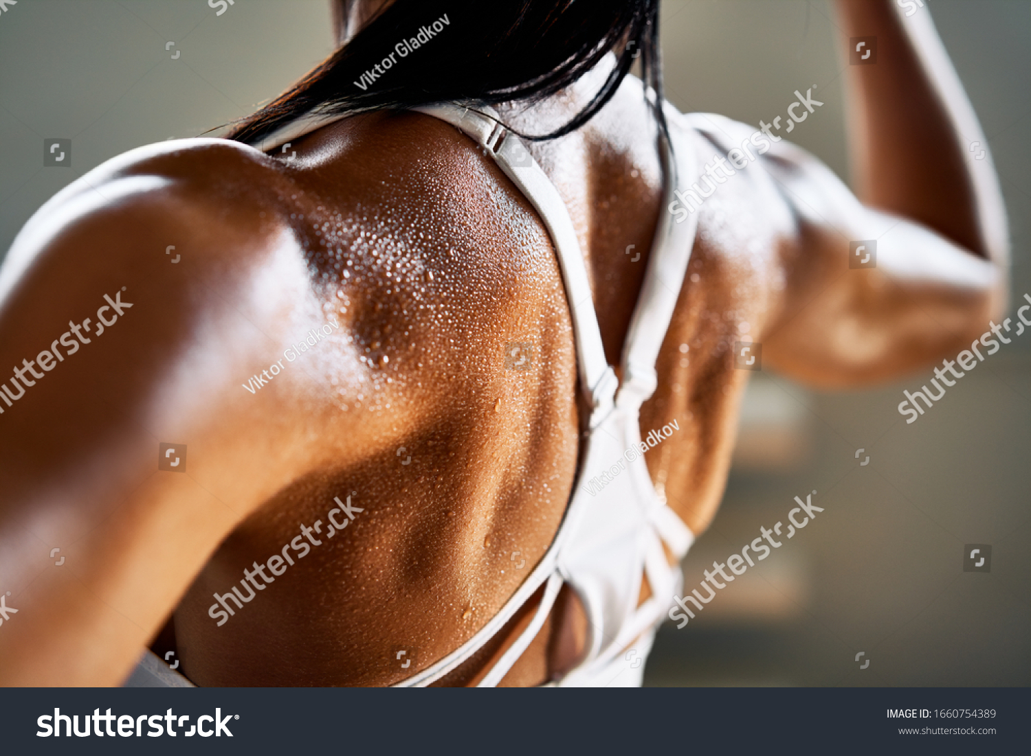 Close up of woman back with flexing her muscles in sweat on skin after workout. Female bodybuilder with perfect biceps                           #1660754389