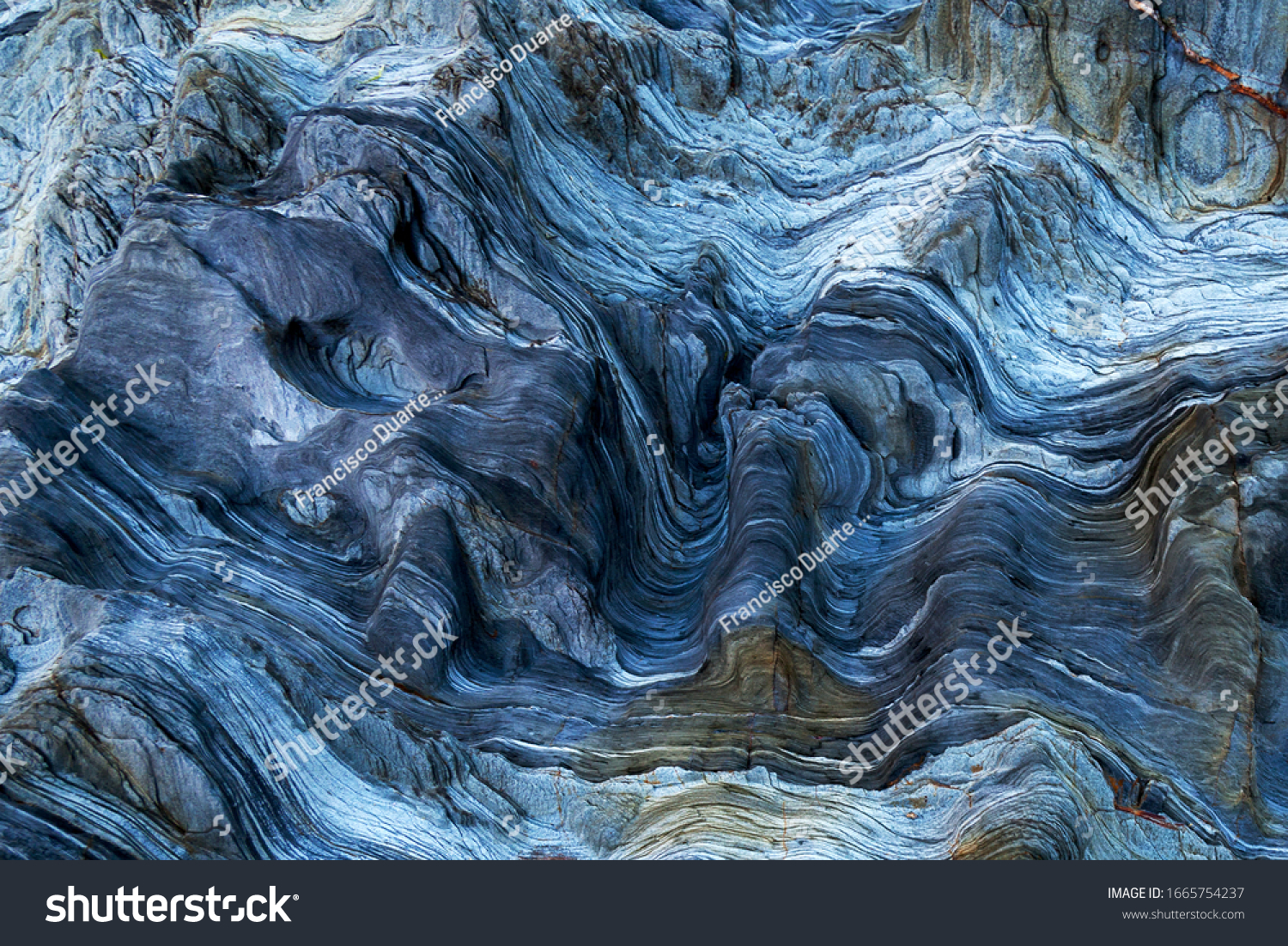 richly detailed rock with variants of blue. Rock full of curves and smooth cuts resulting from the erosive effect of sea. Close up rocks, texture dramatic and colorful erosional water formation. Stone #1665754237