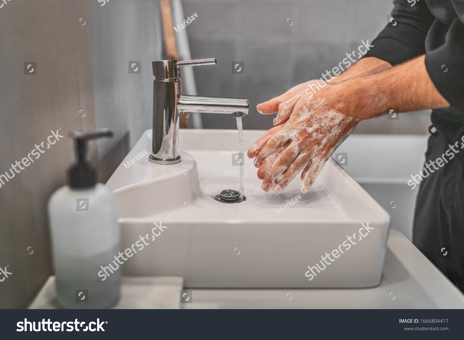 Washing hands with soap and hot water at home bathroom sink man cleansing hand hygiene for coronavirus outbreak prevention. Corona Virus pandemic protection by washing hands frequently. #1666804417