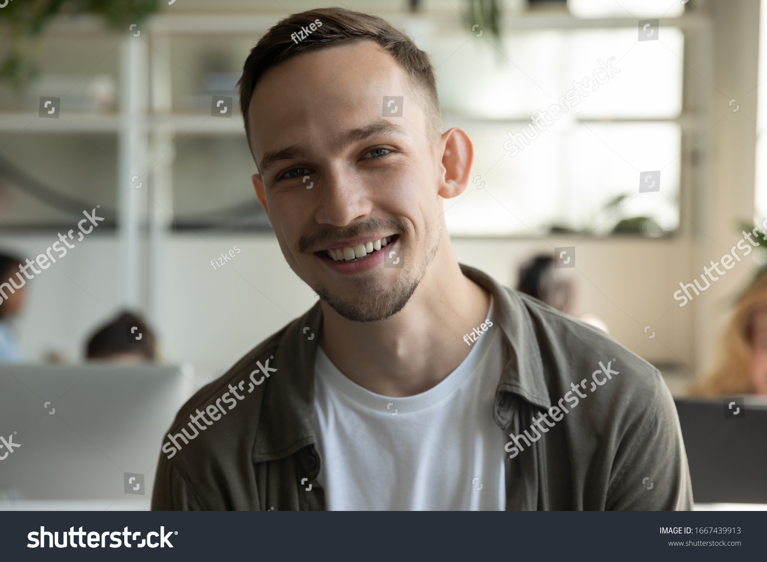 Headshot portrait of smiling millennial male employee talk on video call or web conference in coworking office, profile picture of happy Caucasian young man worker posing in shared workplace #1667439913