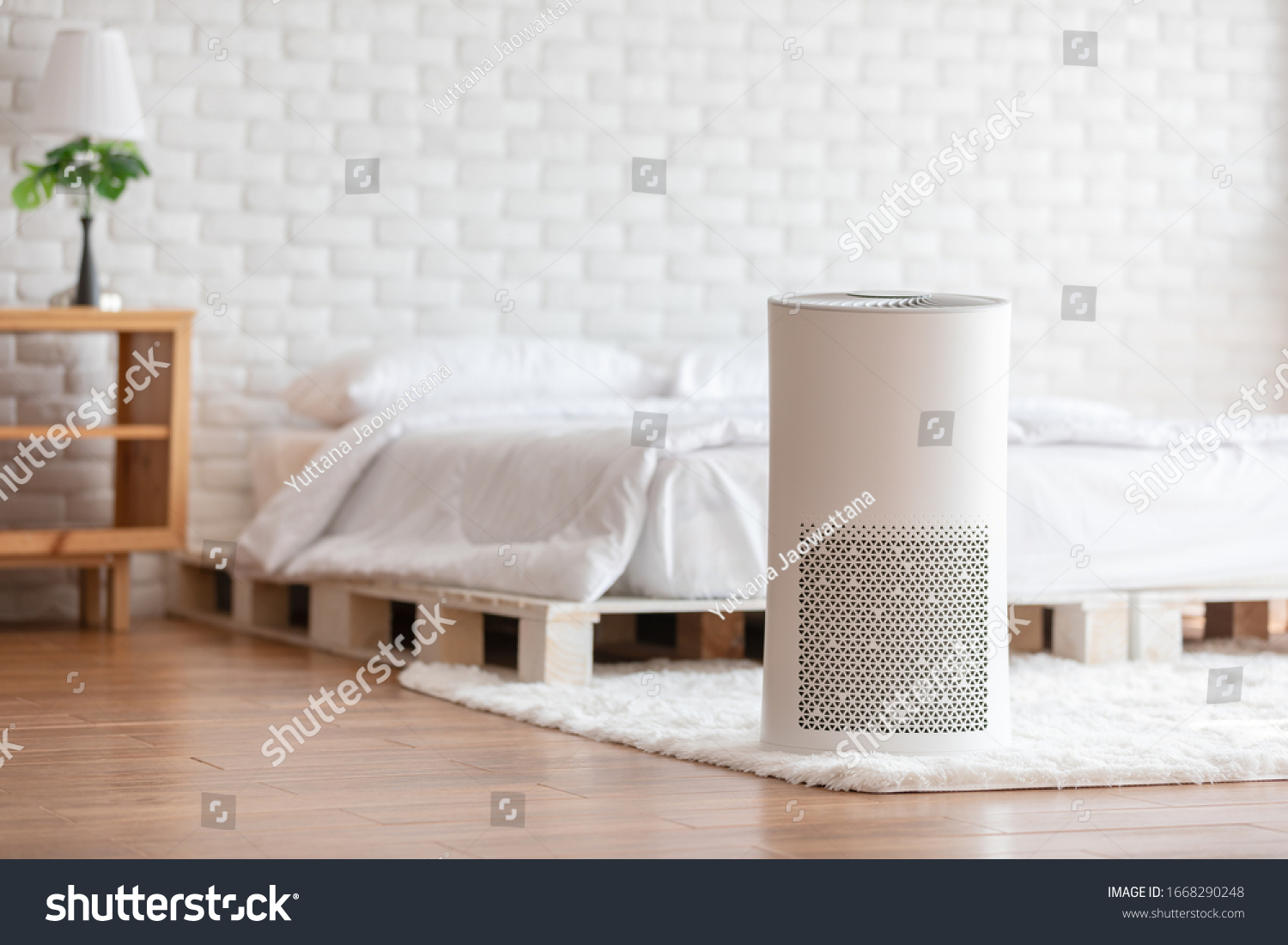 Air purifier in cozy white bedroom for filter and cleaning removing dust PM2.5 HEPA and virus in home,for fresh air and healthy Wellness life.Health care Air Pollution Concept #1668290248