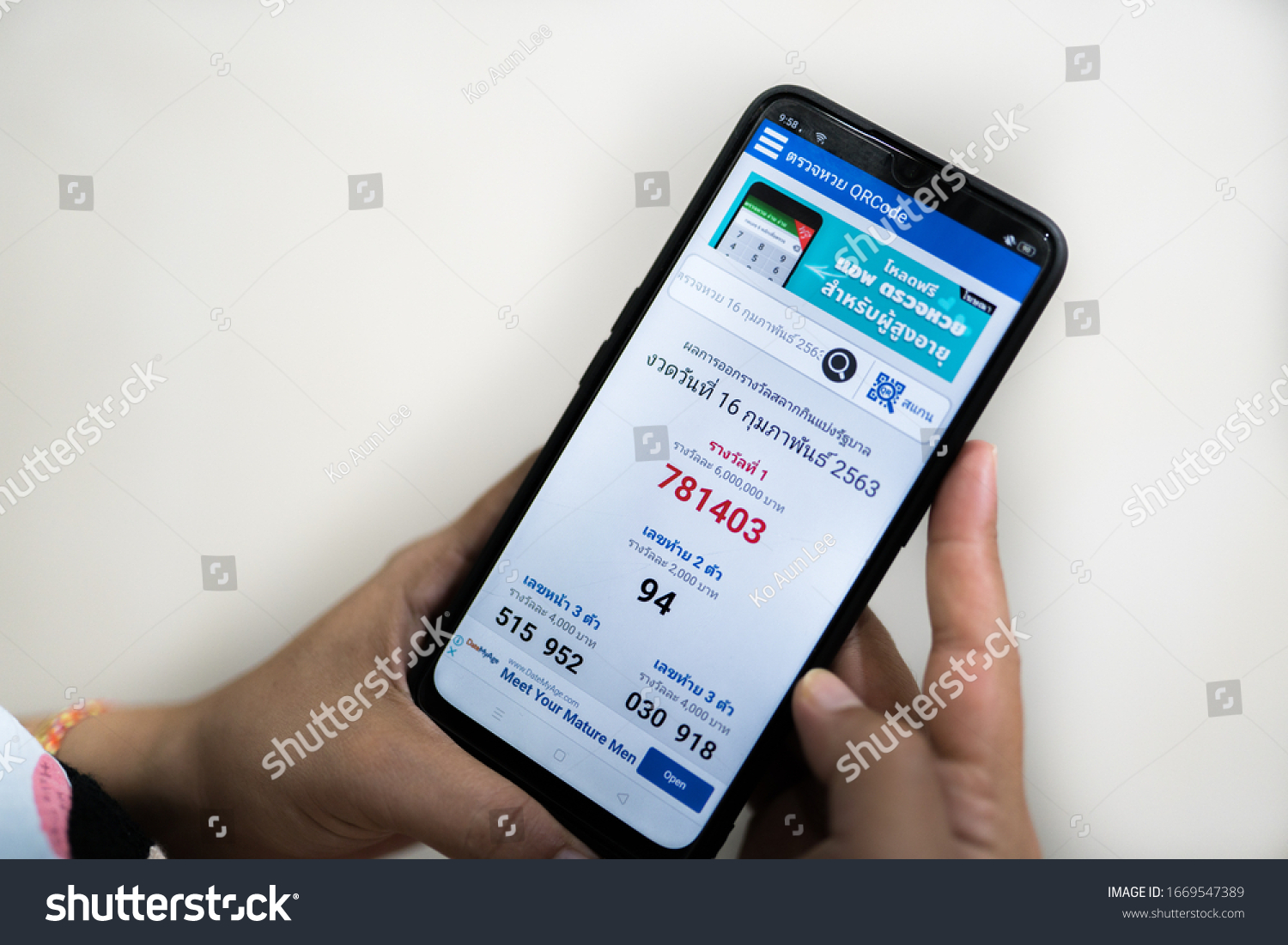 Kedah,Malaysia - 29-02-2020 : hand holding mobile phone with thailand lottery application which results come out every month. #1669547389
