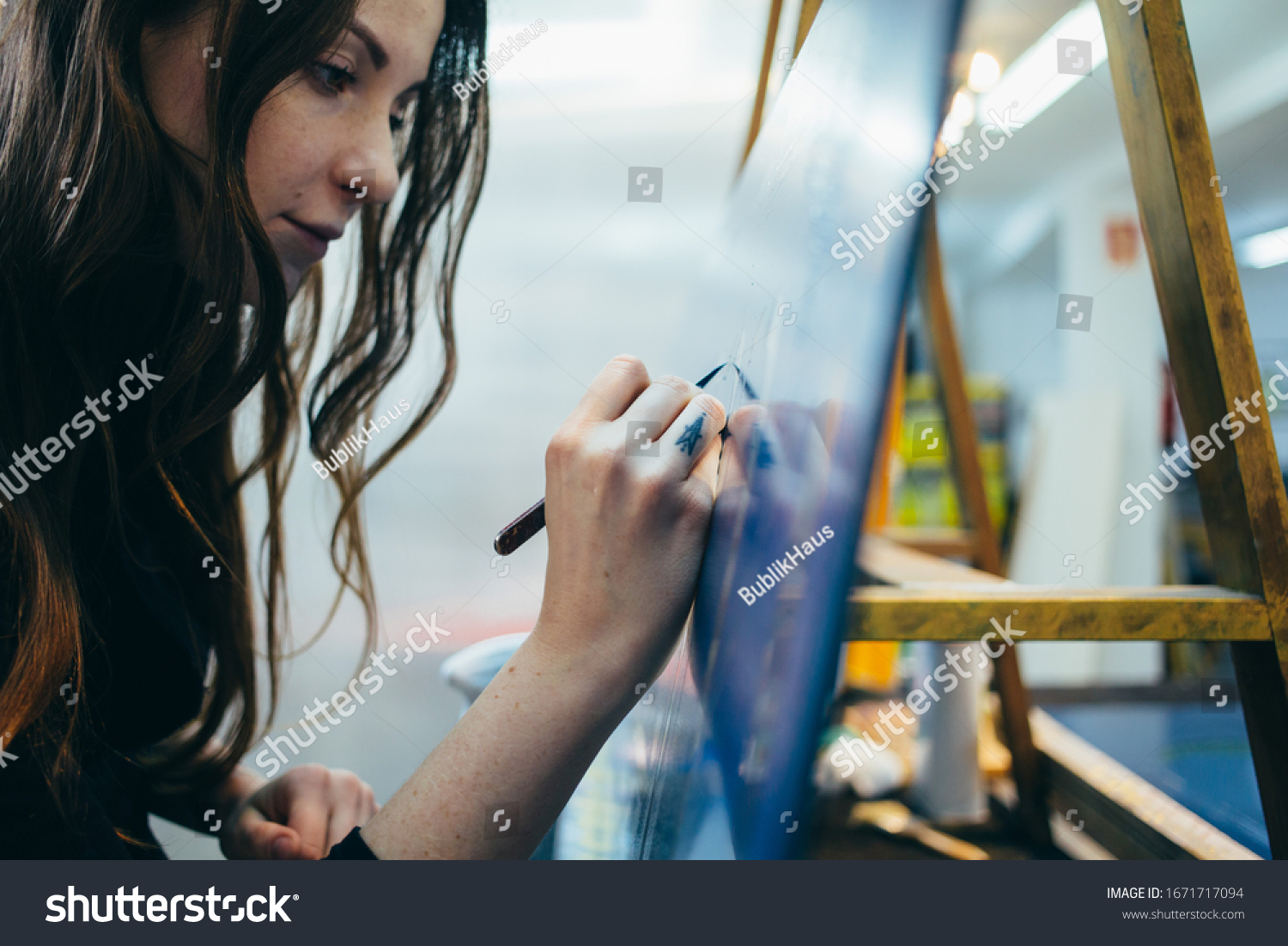Close up portrait of beautiful and authentic young female artist or painter create art piece. Detailed work for personal creative project. Tattoo artist draws artwork #1671717094