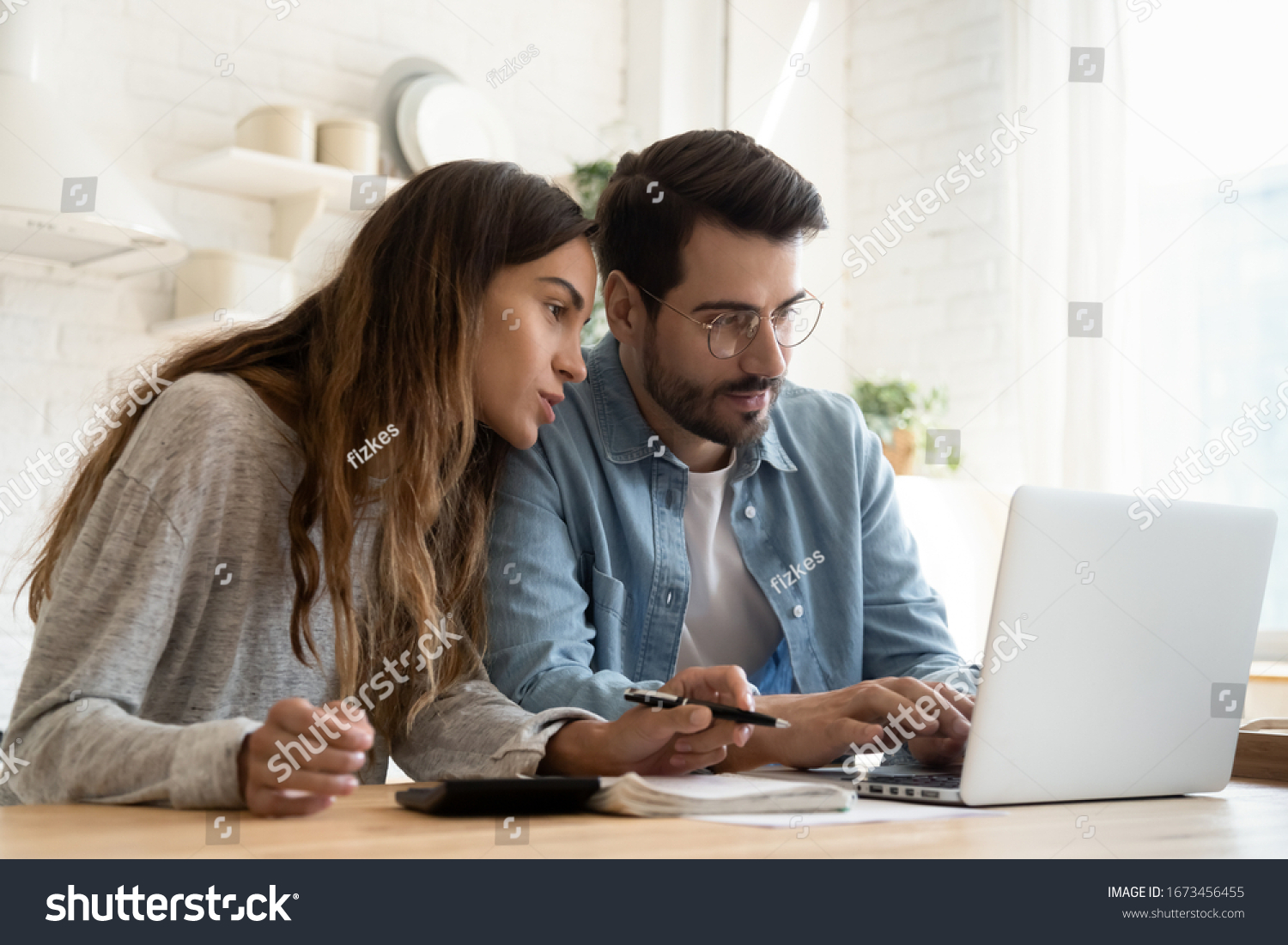 Focused young couple calculating bills, discussing planning budget together, serious wife and husband looking at laptop screen, using online banking services and calculator, checking finances #1673456455