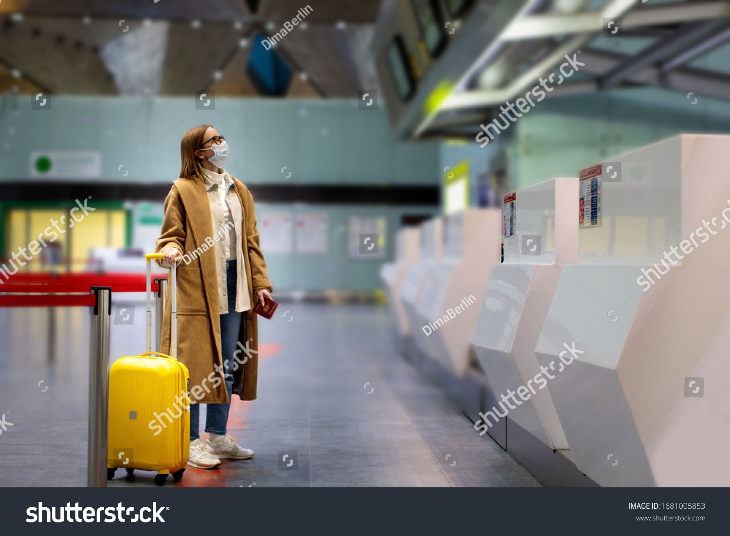 Woman with luggage stands at almost empty check-in counters at the airport terminal due to coronavirus pandemicCovid-19 outbreak travel restrictions. Flight cancellation.Quarantine all over the world #1681005853