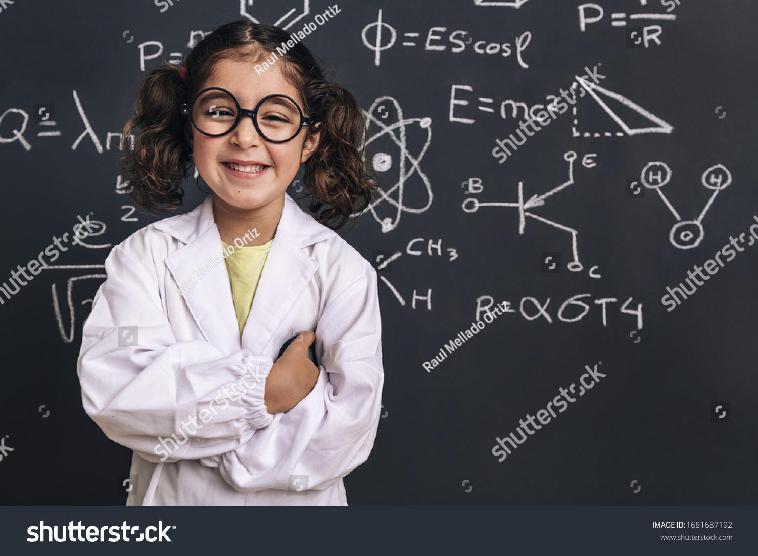smiling little girl science student with glasses in lab coat on school blackboard background with hand drawings science formula pattern, back to school and successful female career concept #1681687192