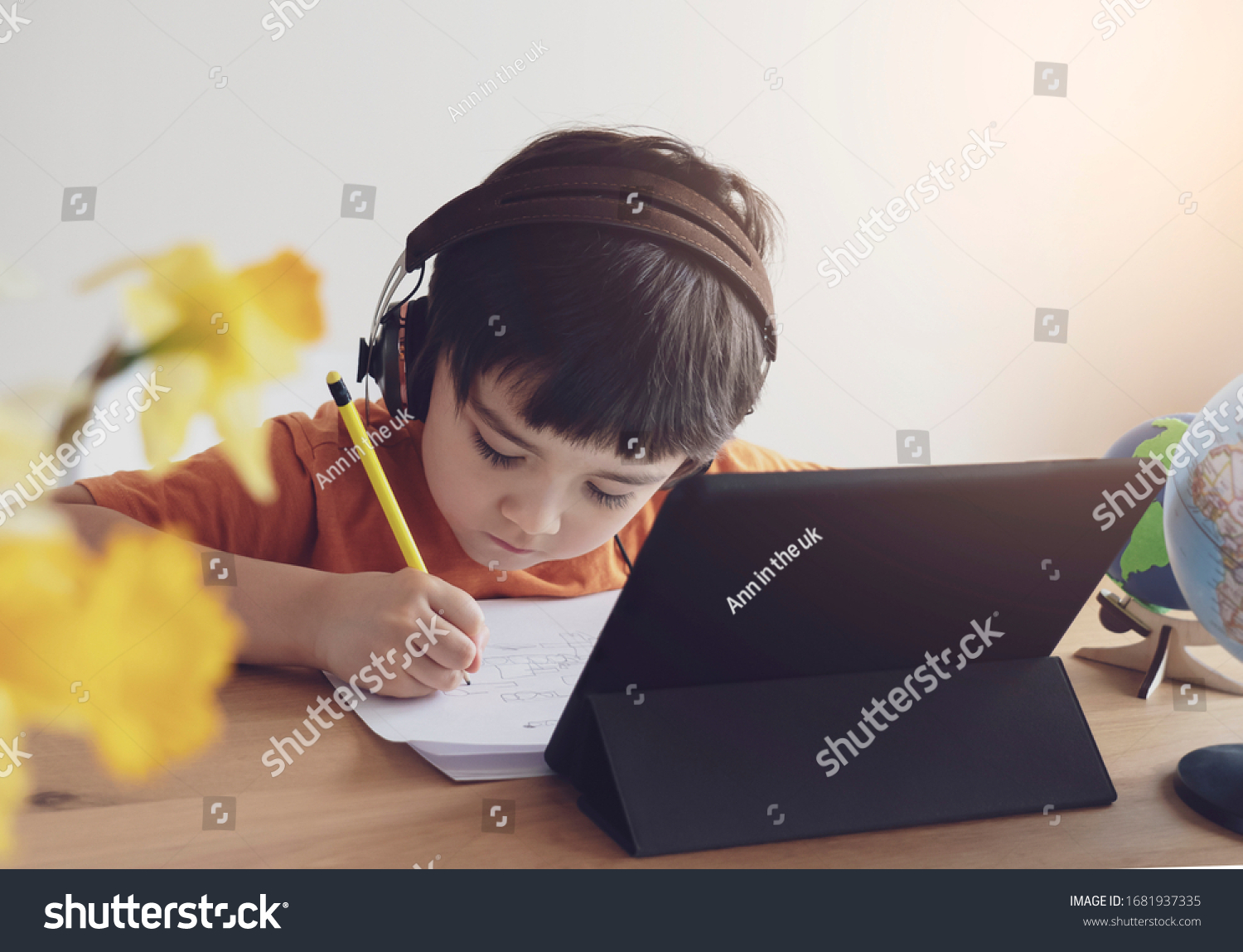 Kid self isolation using tablet for his homework,Child doing using digital tablet searching information on internet during covid 19 lock down,Home schooling,Social Distance,E-learning online education #1681937335