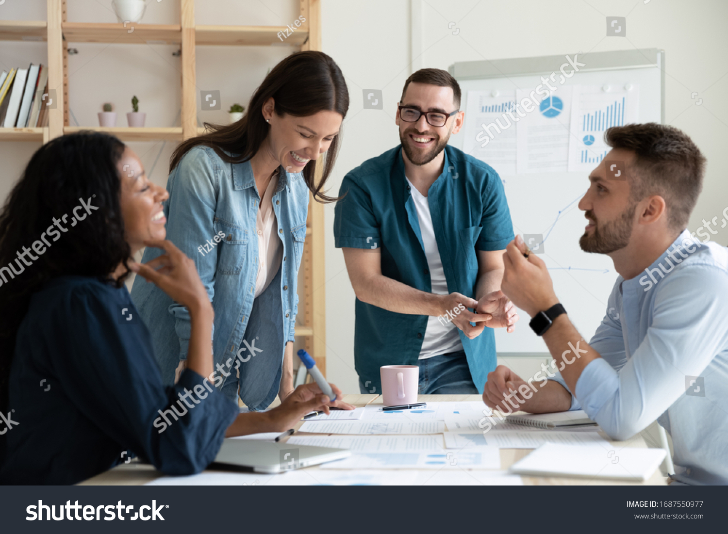 Smiling diverse colleagues gather in boardroom brainstorm discuss financial statistics together, happy multiracial coworkers have fun cooperating working together at office meeting, teamwork concept #1687550977