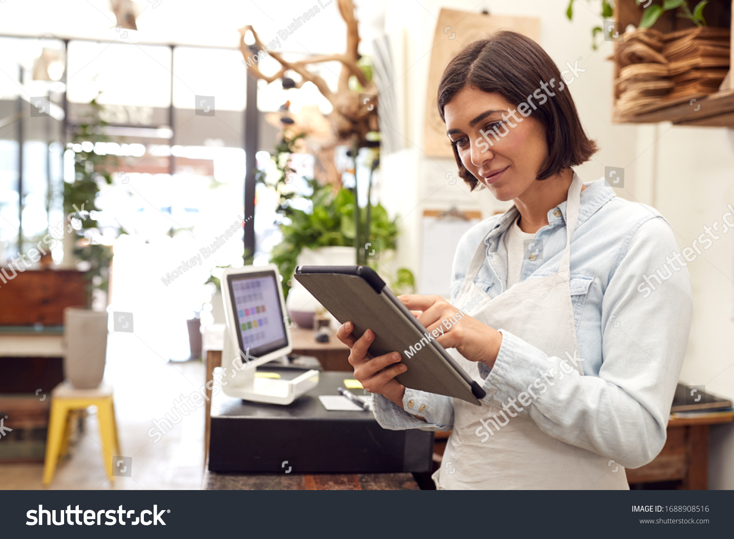 Female Owner With Digital Tablet Standing Behind Sales Desk Of Florists Store #1688908516