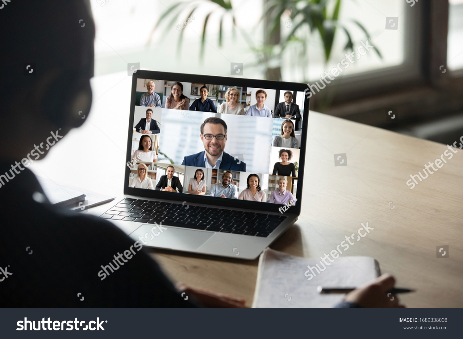 Back view of female employee engaged in team Webcam conference on laptop, have online briefing or consultation from home, woman worker speak talk on group video call with diverse colleagues #1689338008