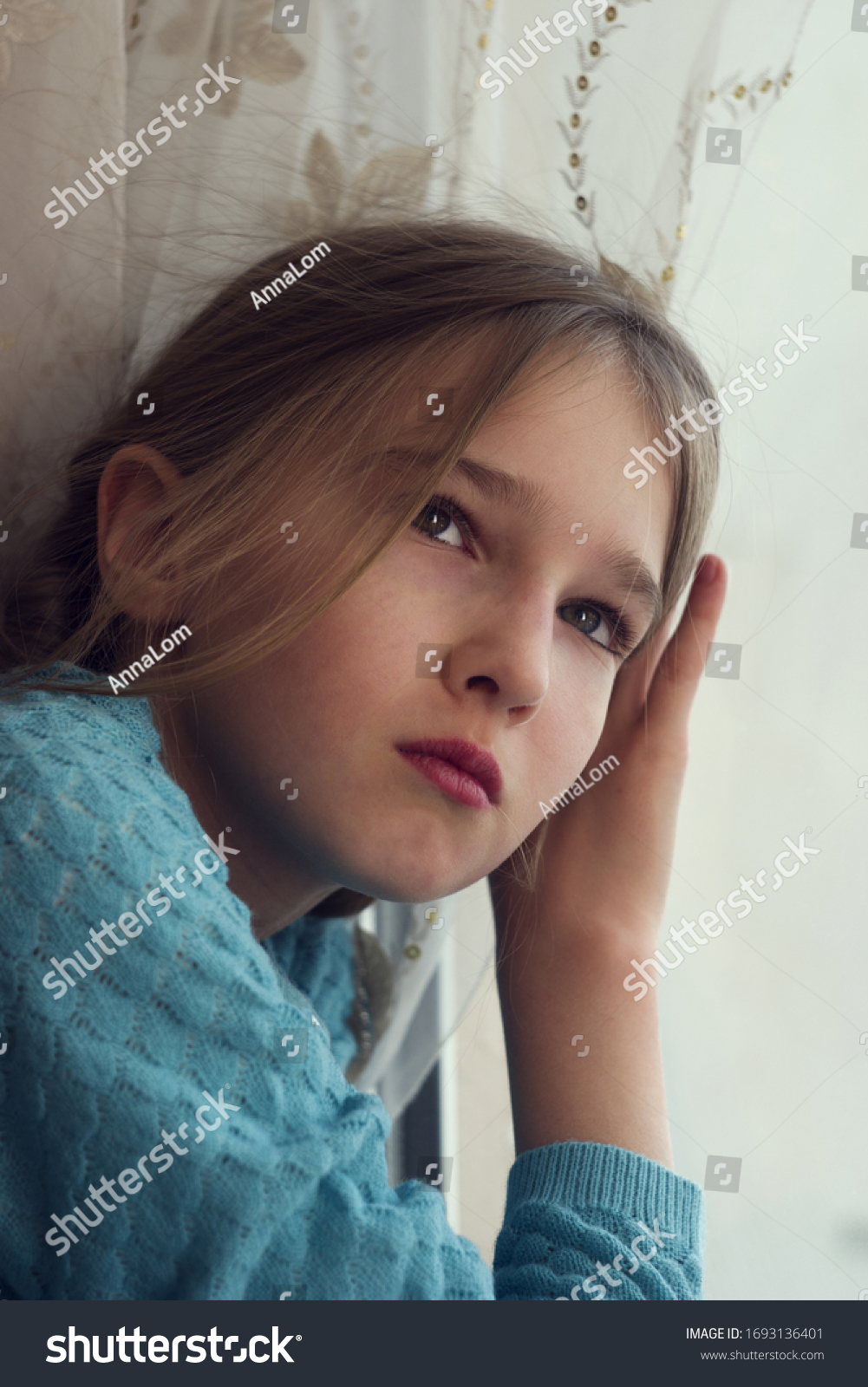 A child looks out of the window with sadness during self-isolation and quarantine. #1693136401