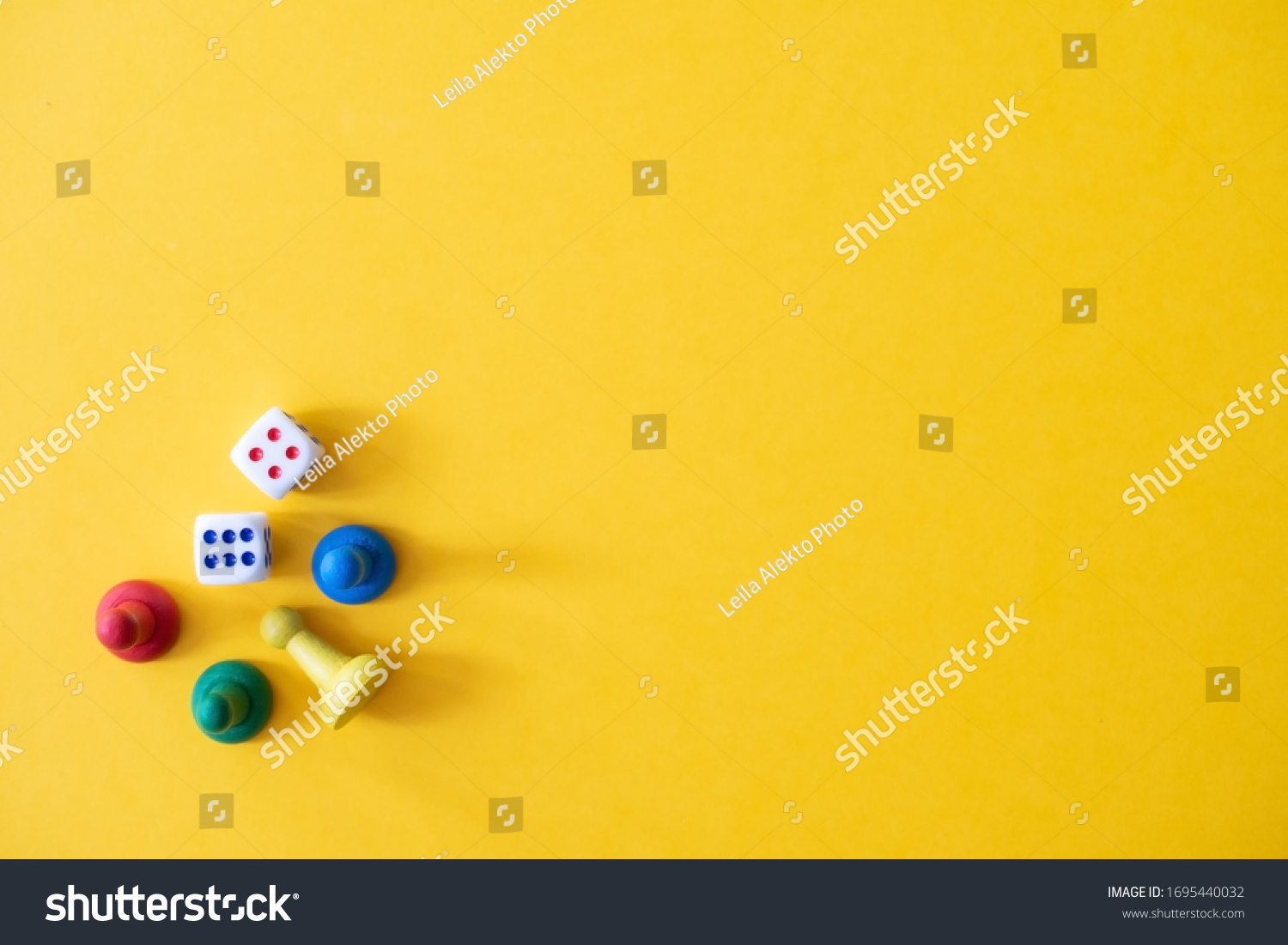 Chess pieces, game chips, Lotto barrels, draughts and playing cubes laid on a yellow background: entertainment, games at home for the whole family, the concept of table games. Board game. Board games #1695440032