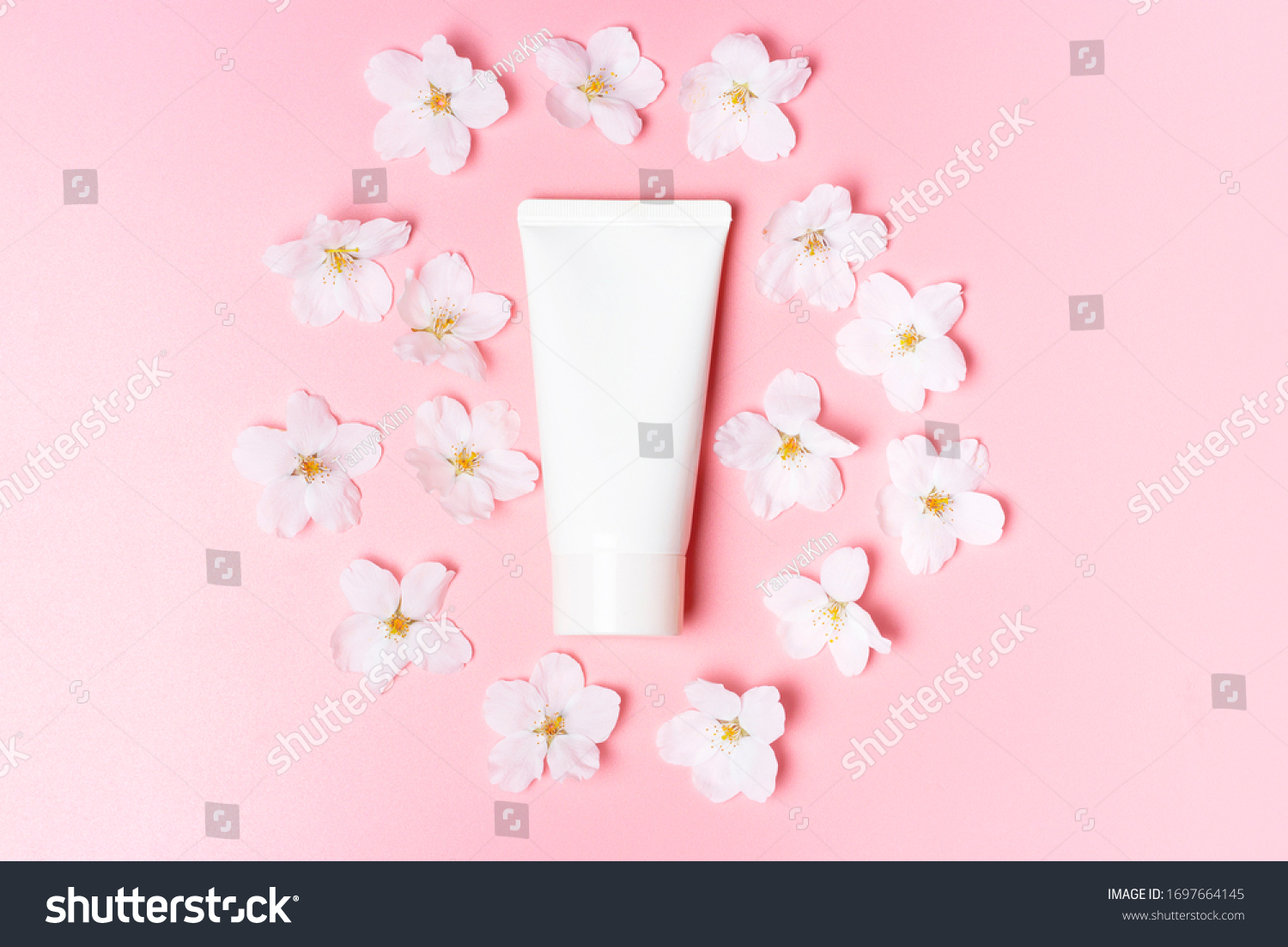 White tube of cream and flowers on a pink background. #1697664145