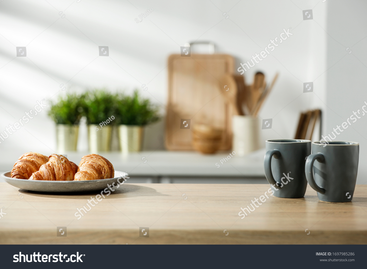 Wooden table in a sunny kitchen in the morning light during breakfast #1697985286