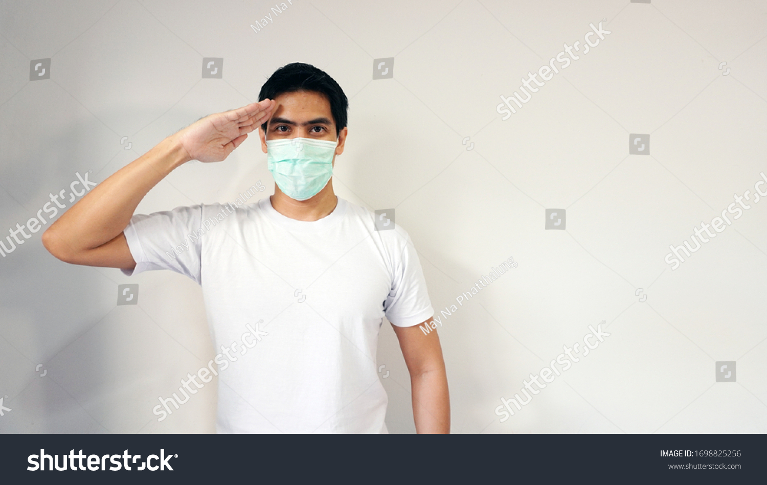 Asian handsome man wearing a medical protective mask act saluting gesture. Concept of showing strong pride protection against pm2.5 and coronavirus covid-19. Isolated on white with copy space #1698825256
