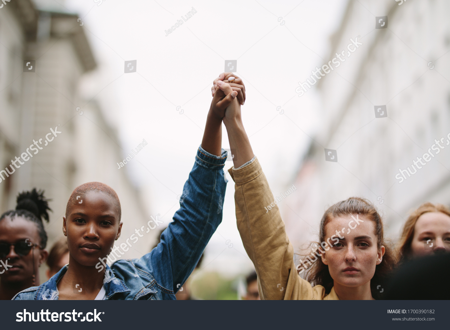 Group of activists with holding hands protesting in the city. Rebellions doing demonstration on the street holding hands. #1700390182