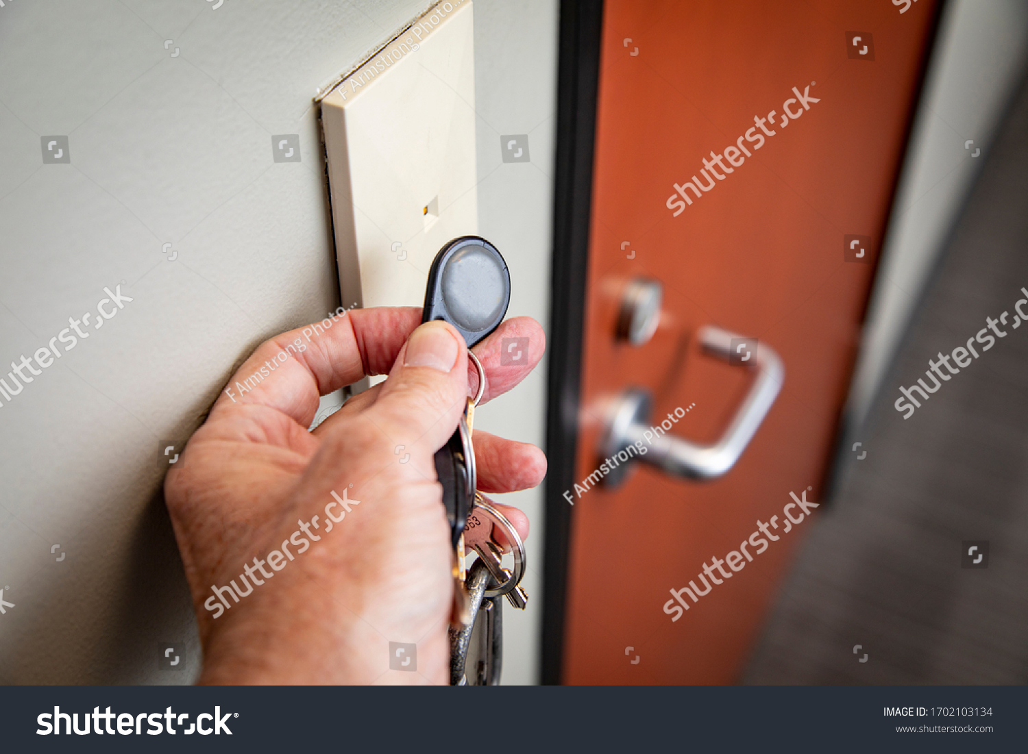 Close up of hand holding key FOB to gain access to an interior office door  #1702103134