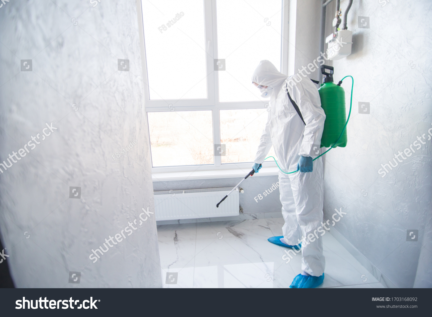 Coronavirus Pandemic. A disinfector in a protective suit and mask sprays disinfectants in house or office. Protection agsinst COVID-19 disease. Prevention of spreding pneumonia virus with surfaces. #1703168092