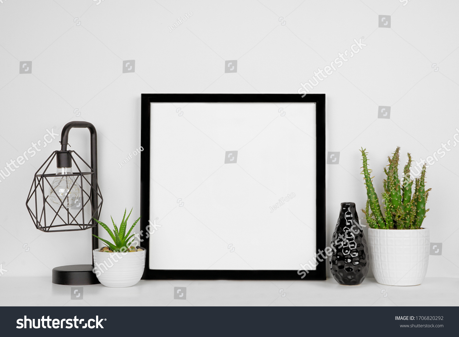 Mock up black square frame with home decor and potted plants. White shelf and wall. Copy space. #1706820292