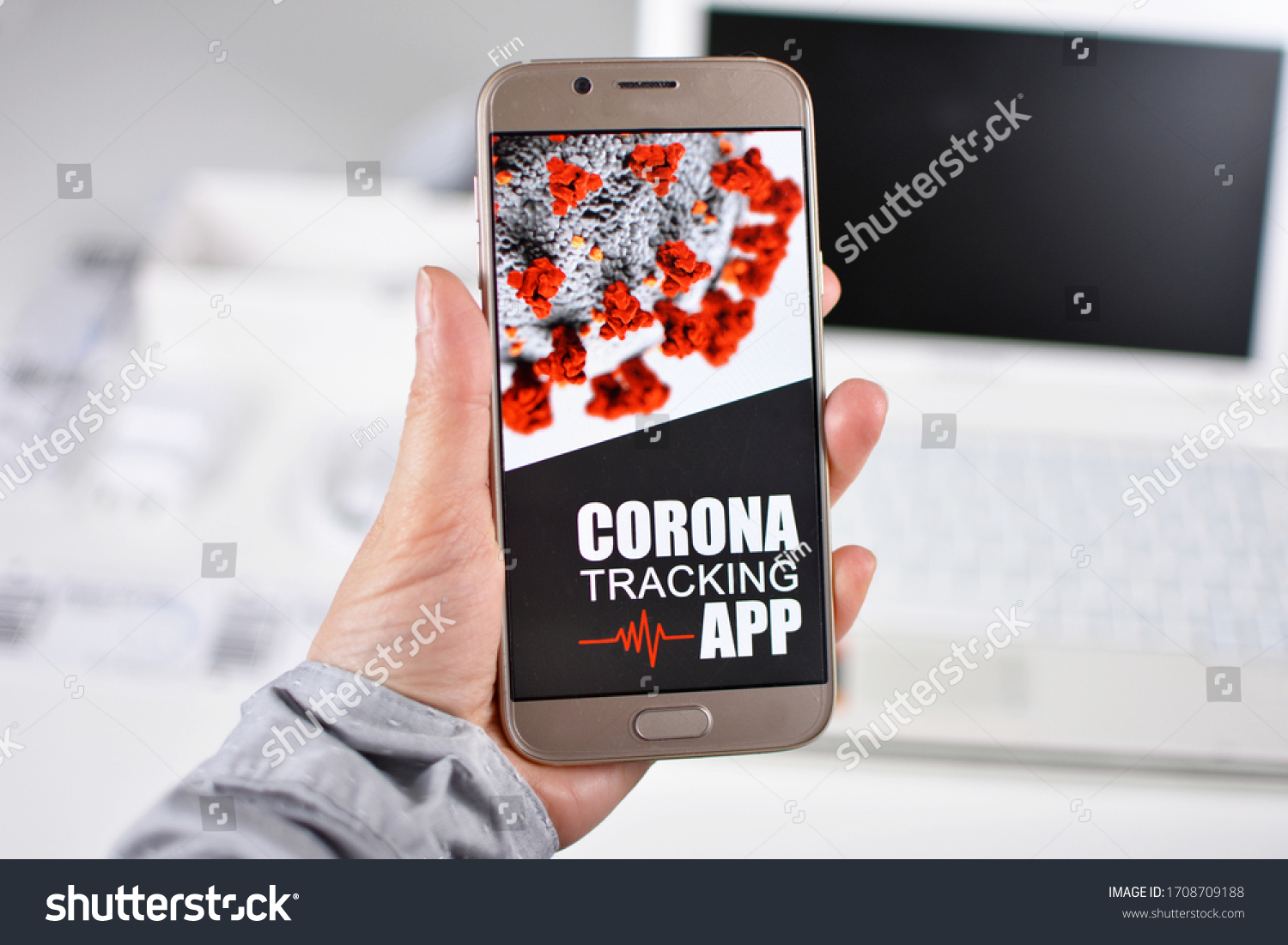 Corona Virus Tracking App concept with hand holding cell phone with application design on screen in front of blurry office background #1708709188