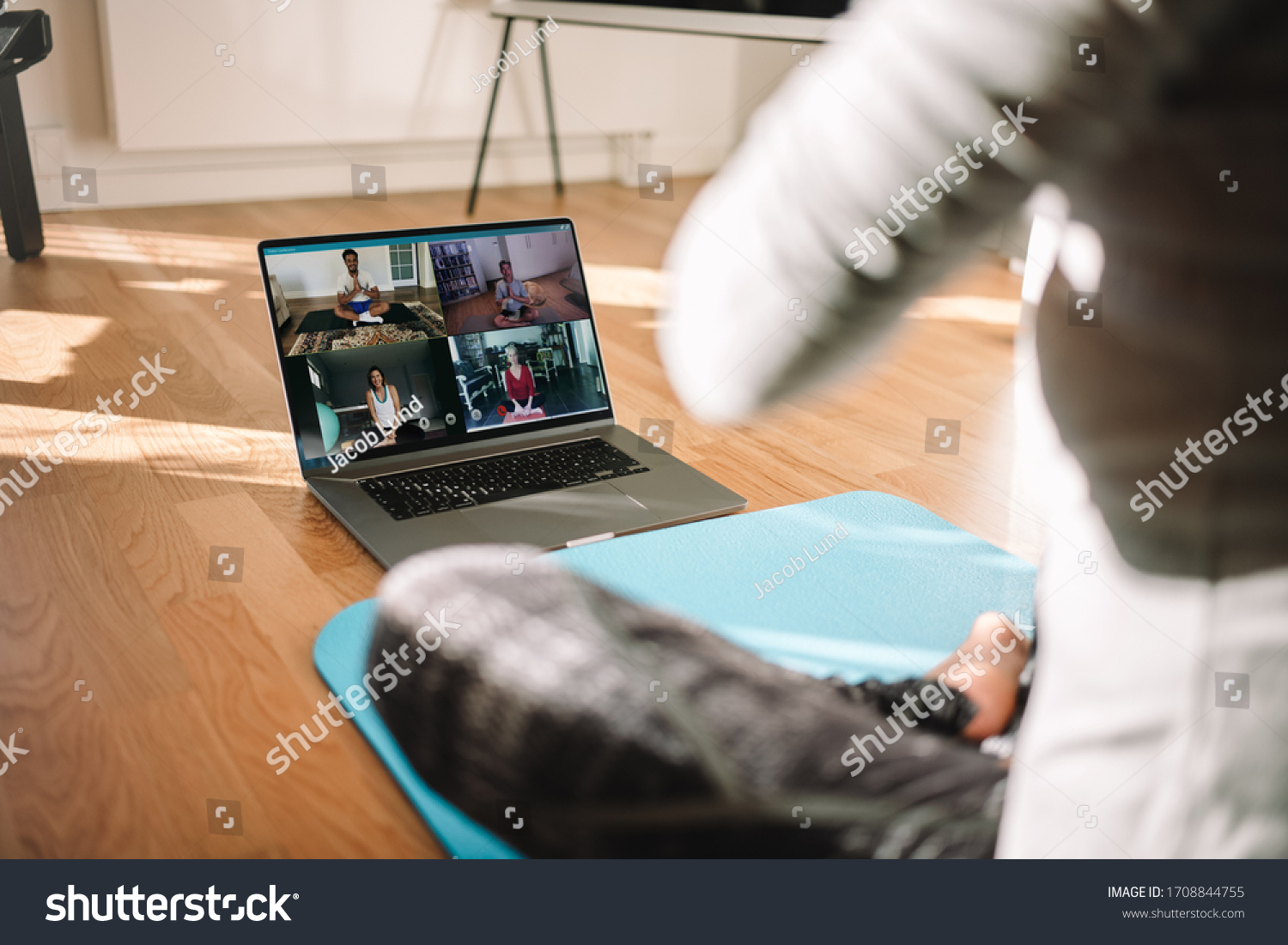 View of a woman conducting virtual fitness class with group of people at home on a video conference. Fitness instructor taking online yoga classes over a video call in laptop. #1708844755