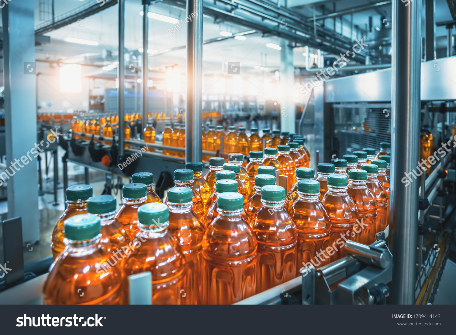 Conveyor belt, juice in bottles, beverage factory interior in blue color, industrial production line. #1709414143