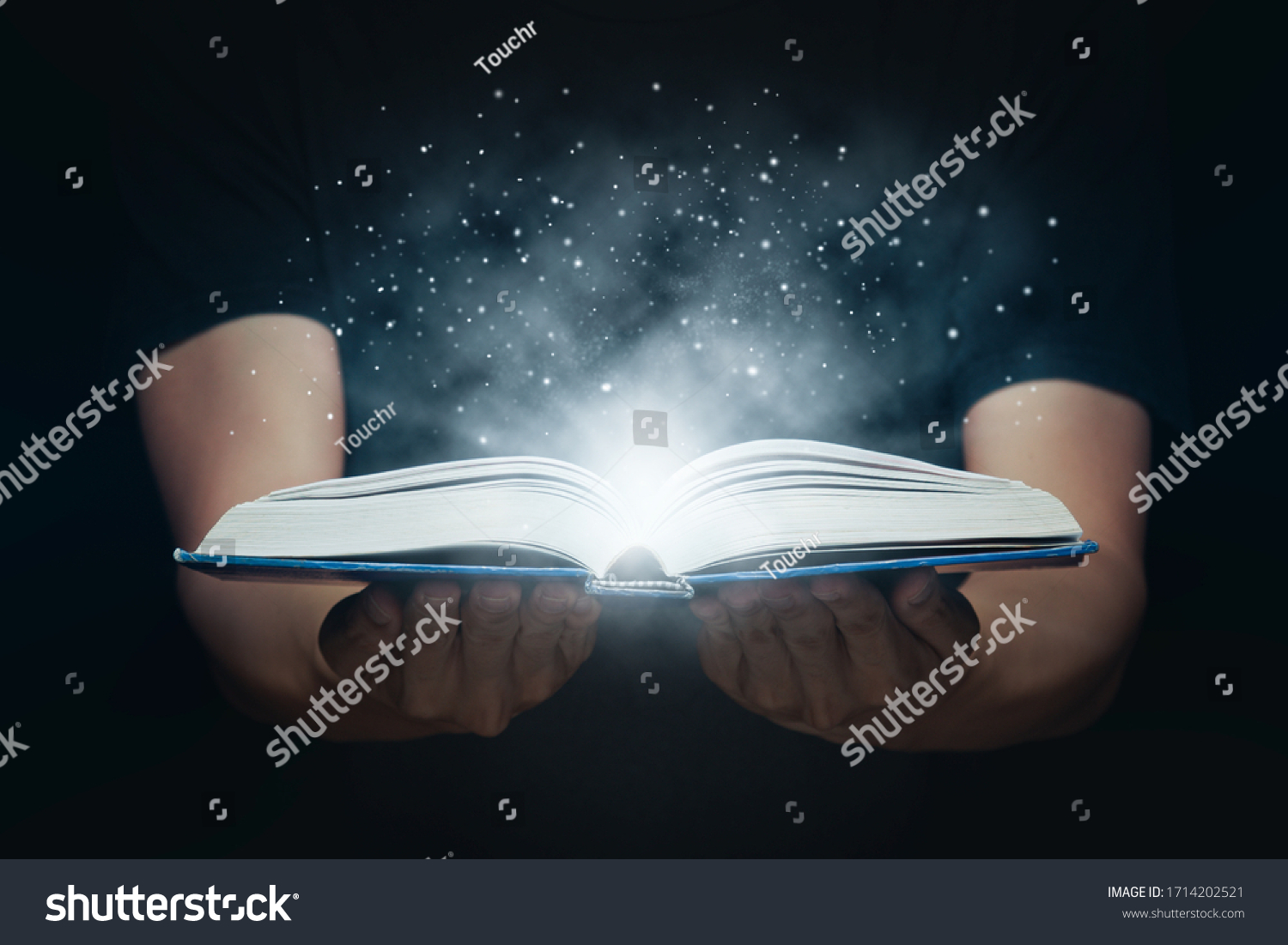 Man opened a magic book with growing lights and magic powder. Learning and education concept. #1714202521
