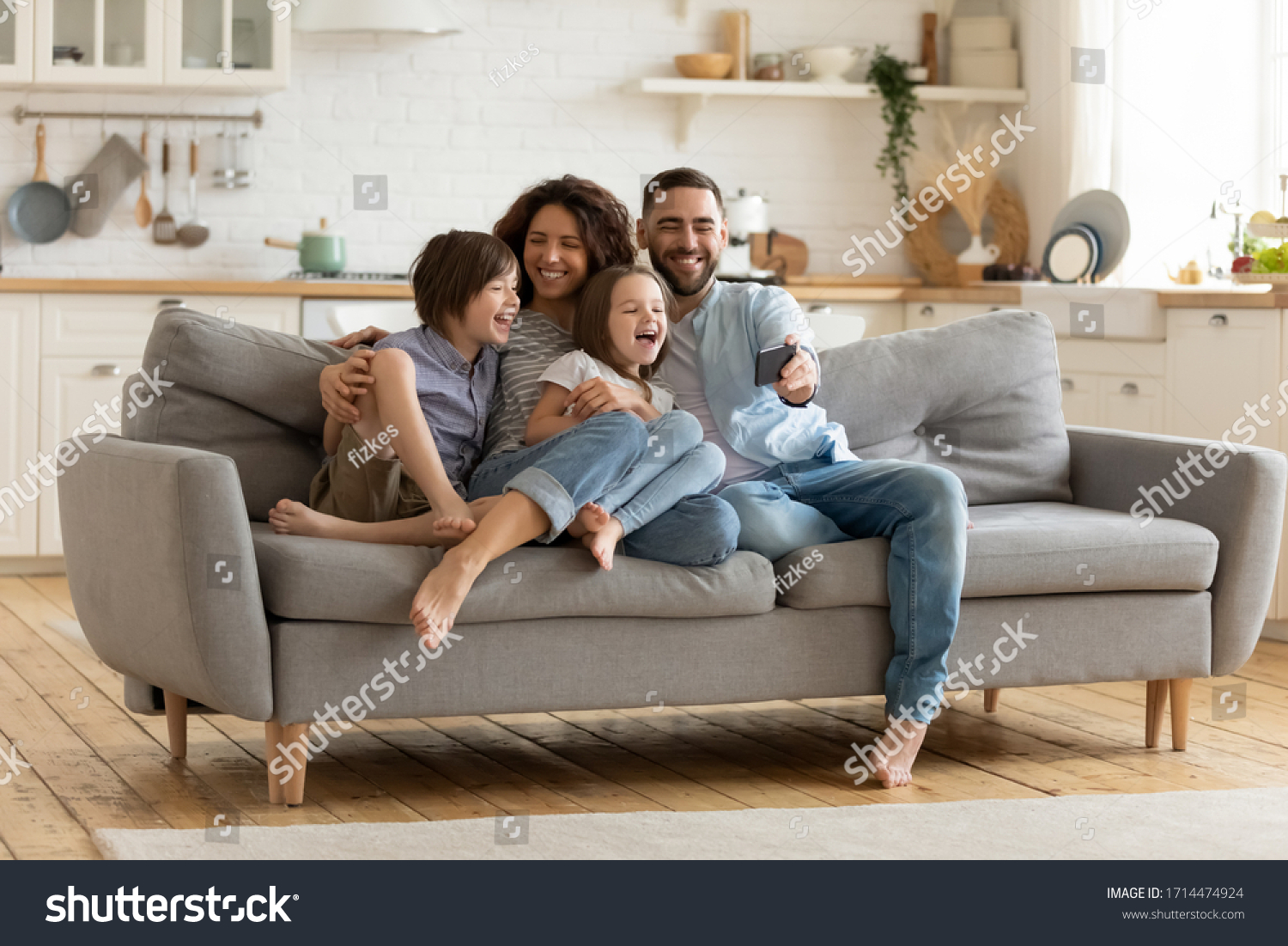 Full length smiling father holding cellphone, making selfie shot, recording video with happy wife and little kids siblings. Excited parents looking at mobile screen with kids, feeling excited. #1714474924