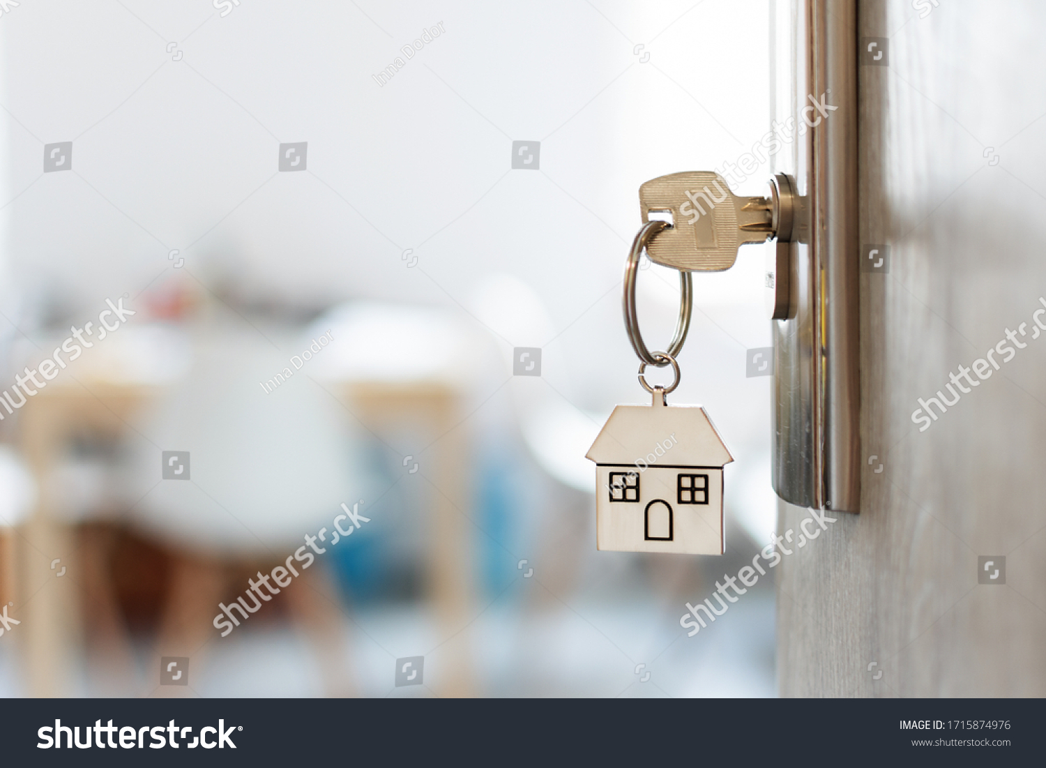 Key with keychain in a house shape in the door keyhole. Buy new home concept. Real estate market. #1715874976