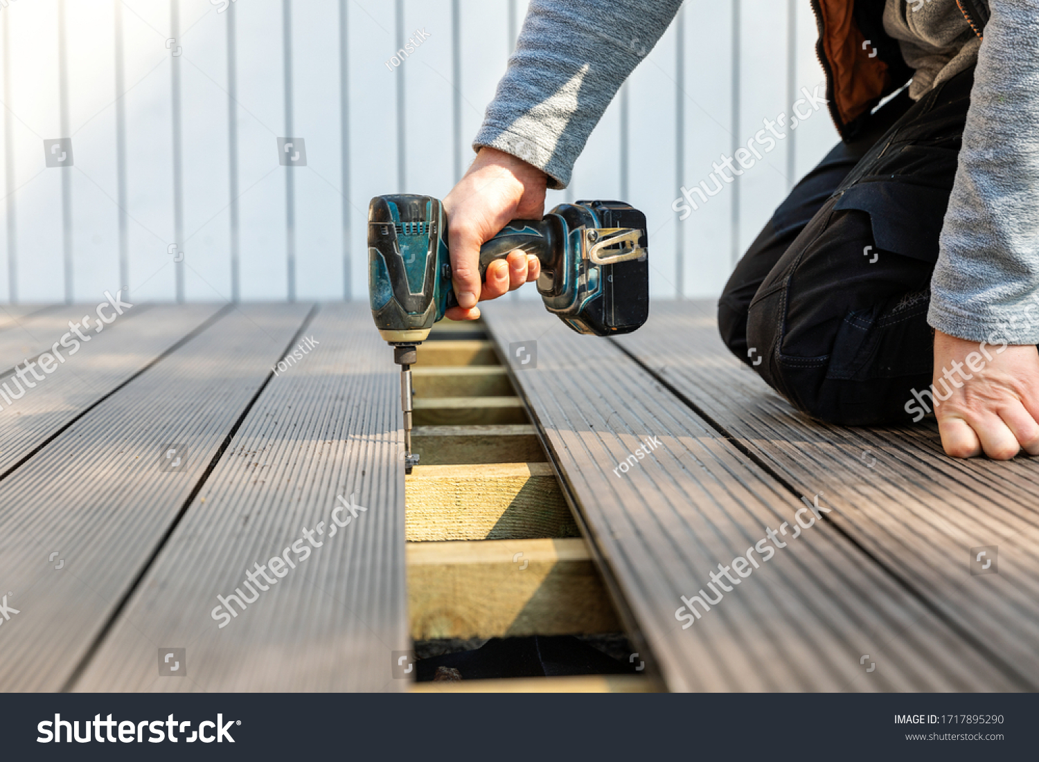 terrace deck construction - man installing wpc composite decking boards #1717895290