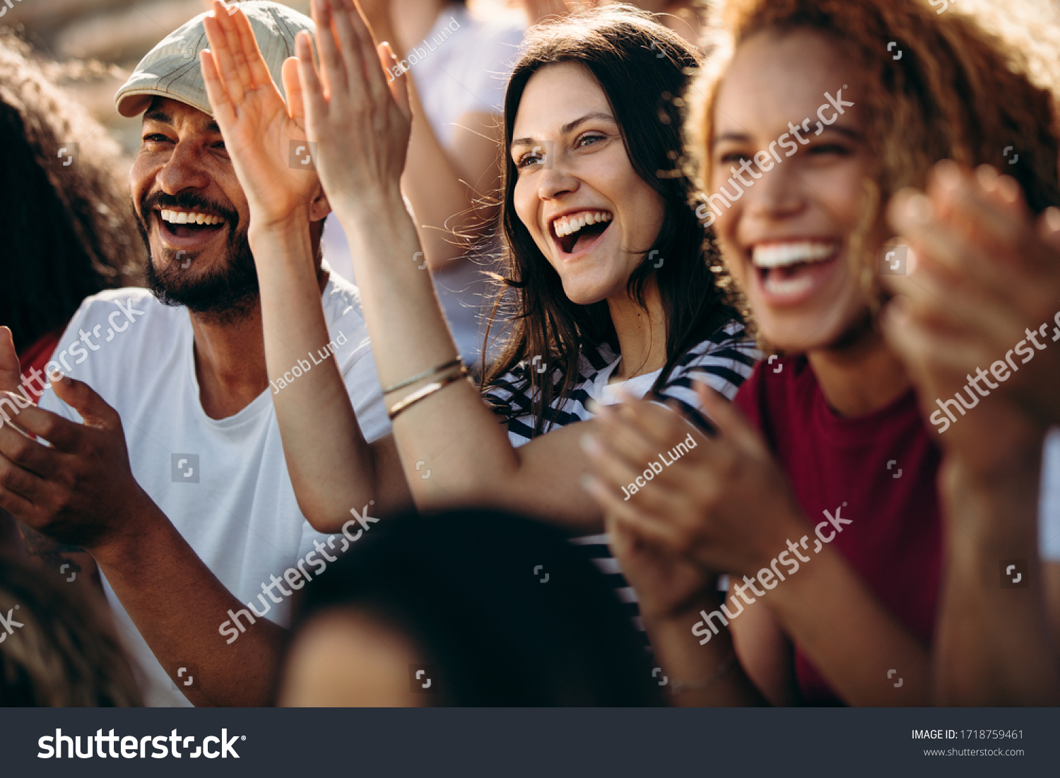 Group of fans watching a sports event in the stands of a stadium. Group of men and women spectators cheering for their team victory. #1718759461