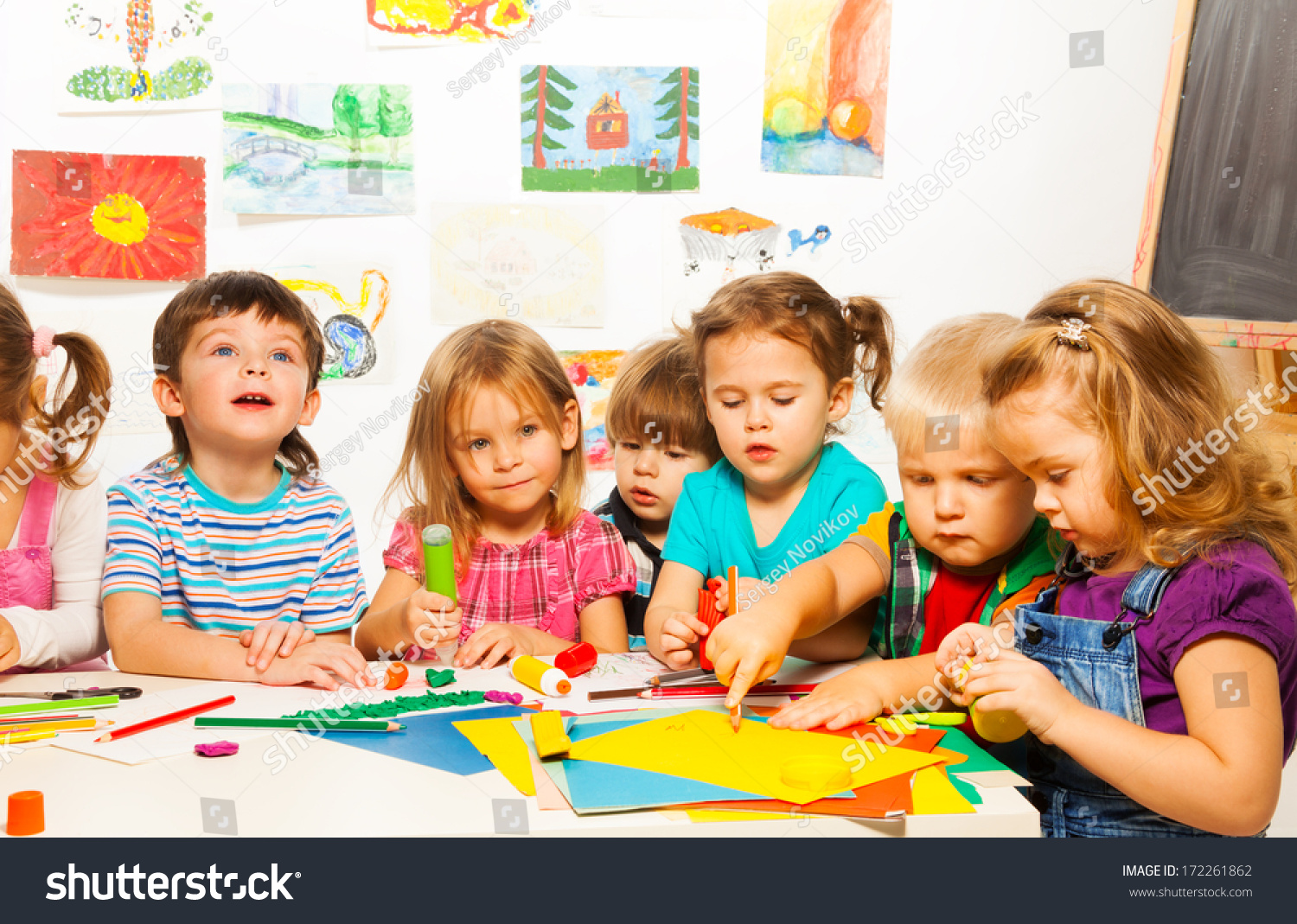 Group of little kids painting with pencils and gluing with glue stick on art class in kindergarten #172261862