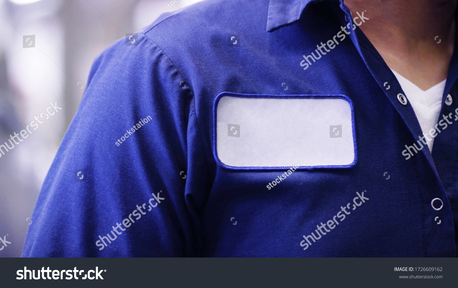 unrecognizable man wearing blue uniform shirt with empty name white tag or patch, worker or employee Identification. #1726609162