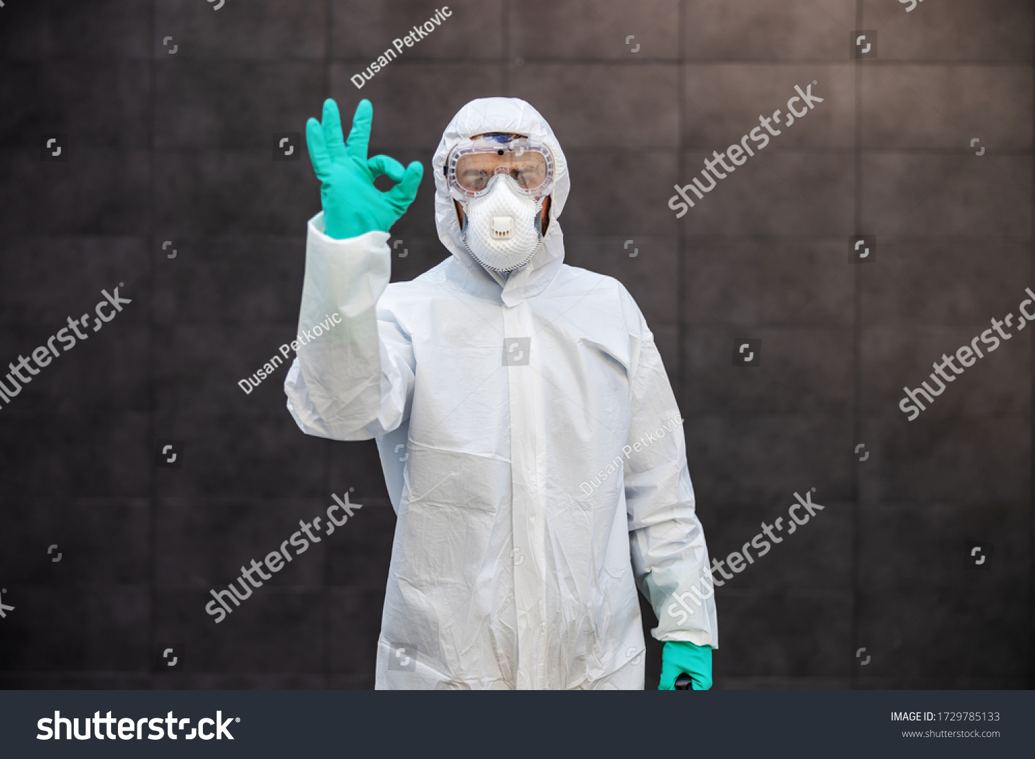 Portrait of man in sterile uniform and mask standing outdoors and showing okay sign. Surfaces are all sterilized from corona virus/ covid-19. #1729785133