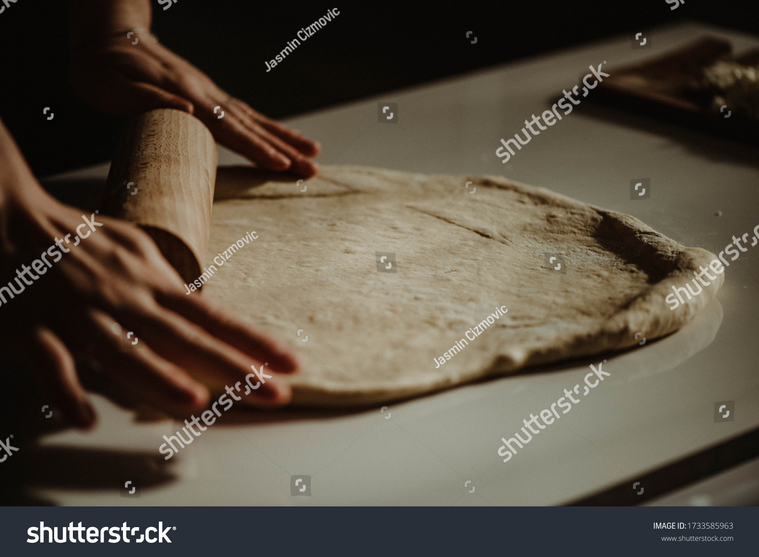Wife making a homemade doughy pastry food with smoked cheese during Ramadan for dinner during the sunset light in the home on the wooden table #1733585963